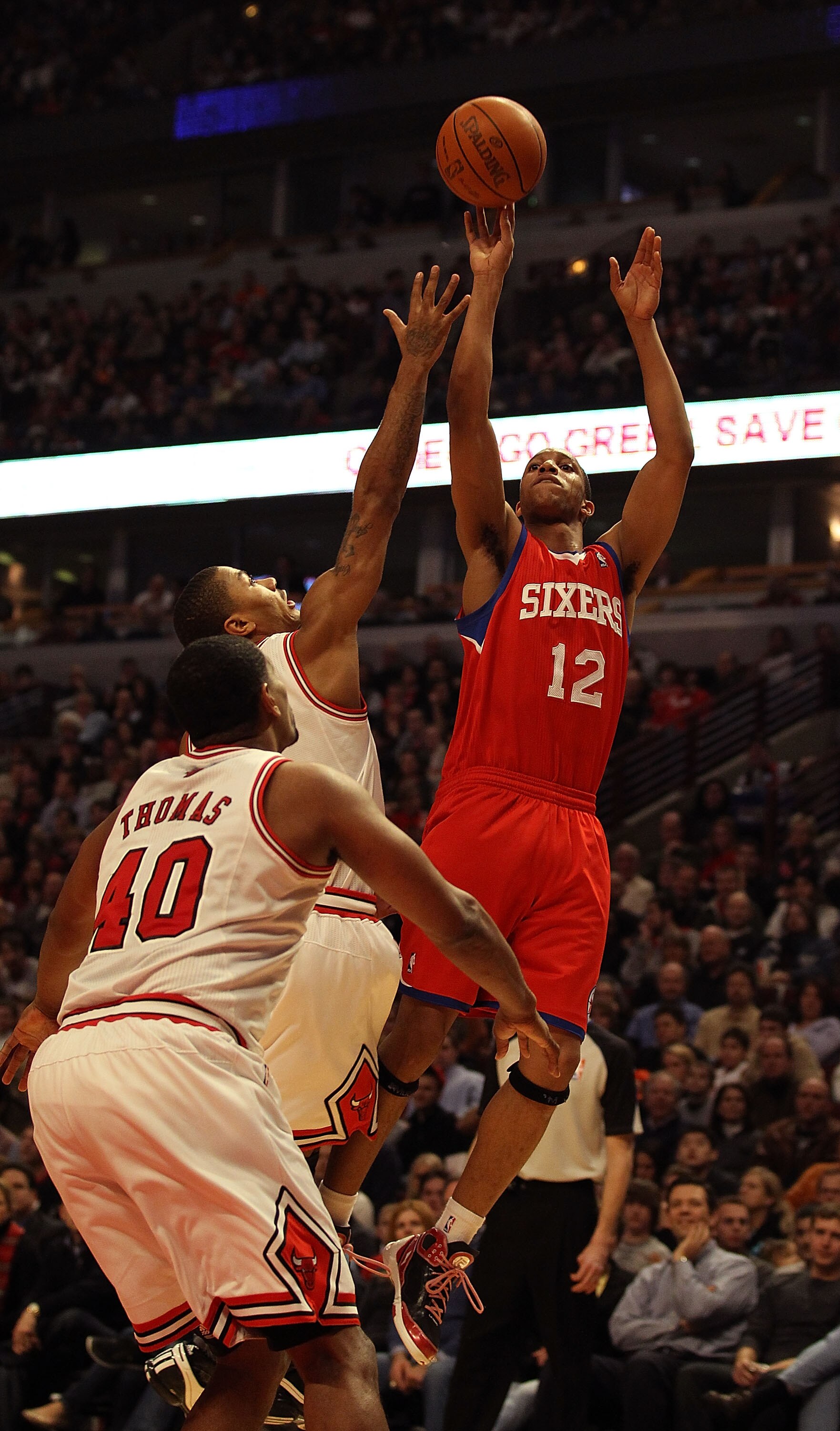 CHICAGO, IL - DECEMBER 21: Evan Turner #12 of the Philadelphia 76ers puts up a shot over Derrick Rose #1 and Kurt Thomas #40 of the Chicago Bulls at the United Center on December 21, 2010 in Chicago, Illinois. NOTE TO USER: User expressly acknowledges and