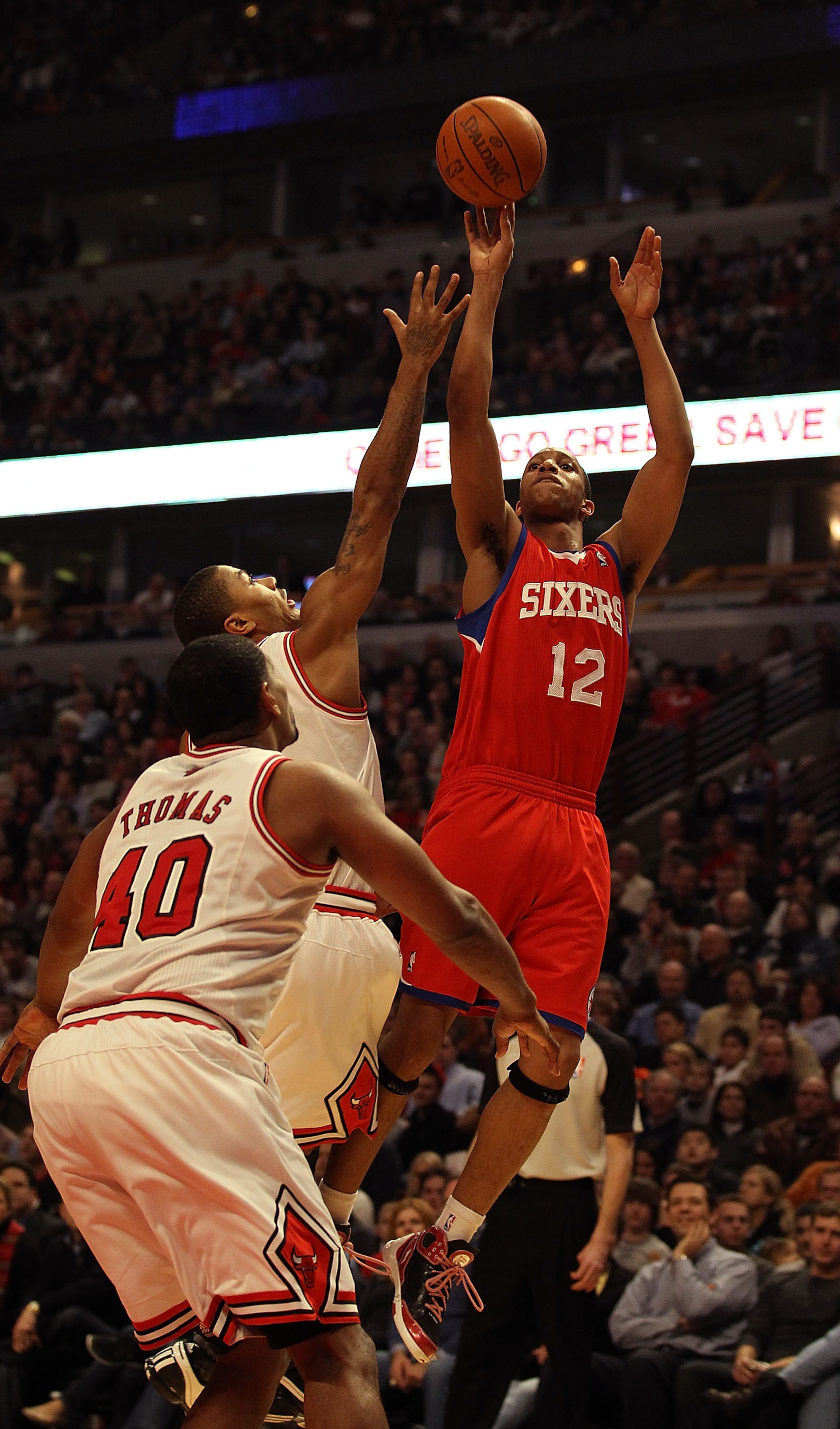 CHICAGO, IL - DECEMBER 21: Evan Turner #12 of the Philadelphia 76ers puts up a shot over Derrick Rose #1 and Kurt Thomas #40 of the Chicago Bulls at the United Center on December 21, 2010 in Chicago, Illinois. NOTE TO USER: User expressly acknowledges and