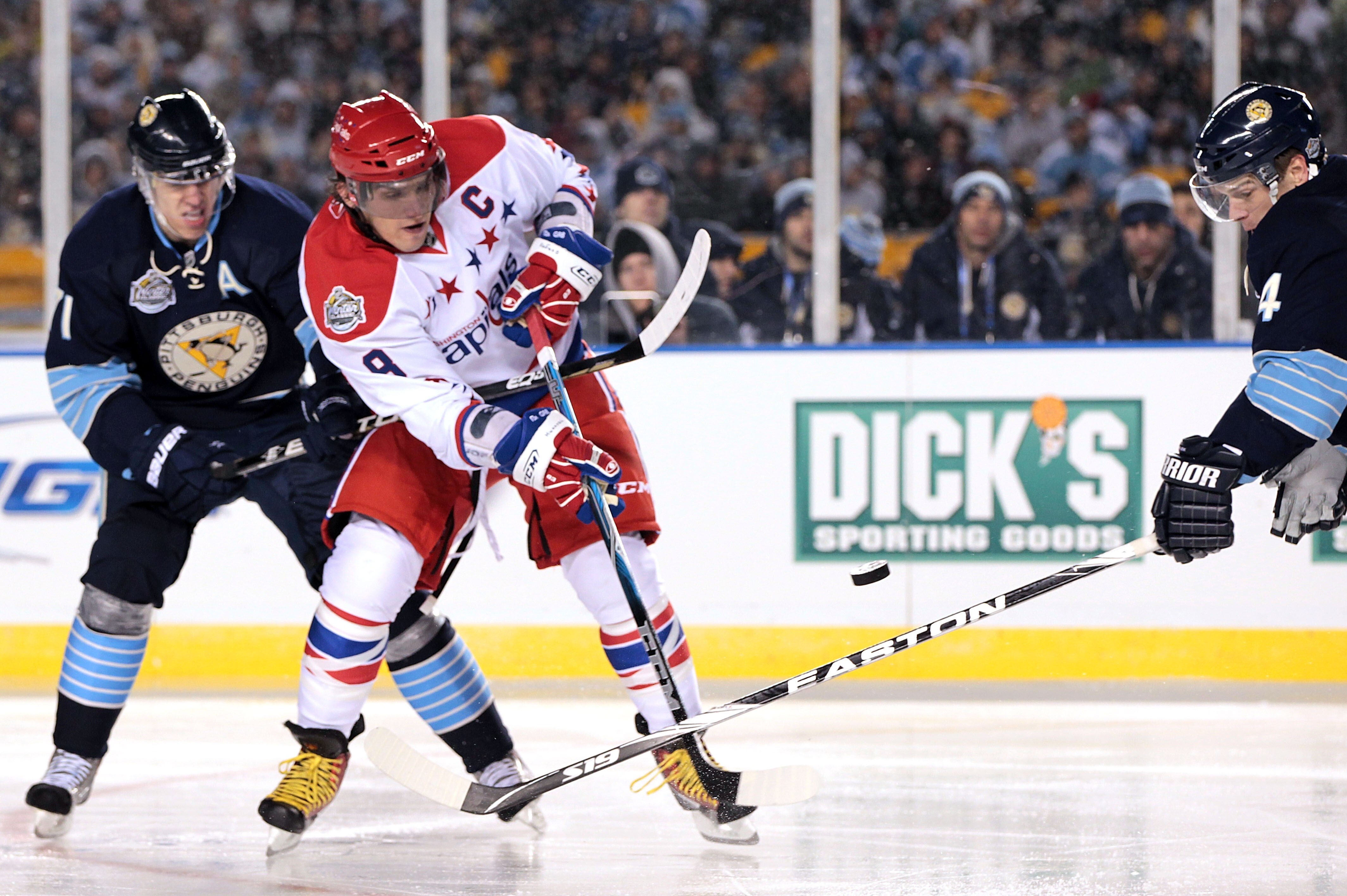 PITTSBURGH, PA - JANUARY 01:  Alex Ovechkin #8 of the Washington Capitals passes against Zbynek Michalek #4 and Evgeni Malkin #71 of the Pittsburgh Penguins during the 2011 NHL Bridgestone Winter Classic at Heinz Field on January 1, 2011 in Pittsburgh, Pe