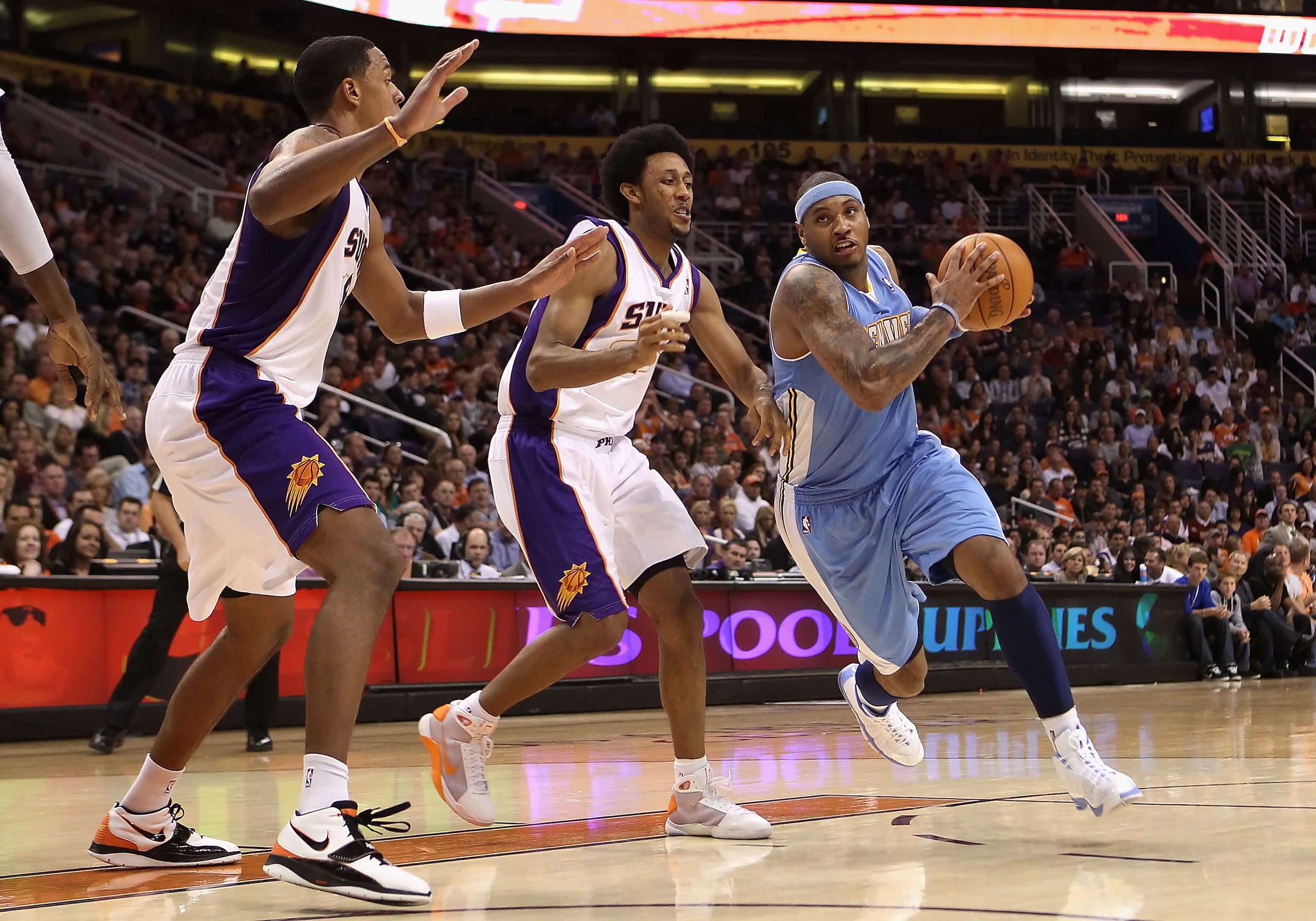 PHOENIX - NOVEMBER 15:  Carmelo Anthony #15 of the Denver Nuggets drives the ball past Josh Childress #1 of the Phoenix Suns during the NBA game at US Airways Center on November 15, 2010 in Phoenix, Arizona.  The Suns defeated the Nuggets 100-94.  NOTE TO