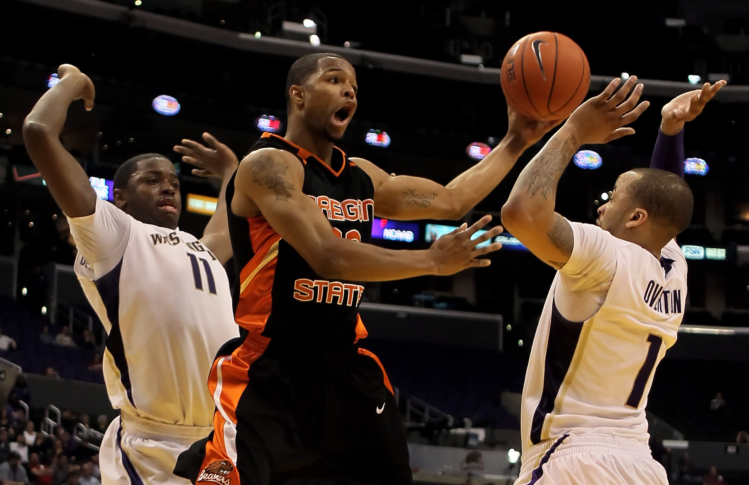 LOS ANGELES, CA - MARCH 11:  Calvin Haynes #22 of the Oregon State Beavers drives between Matthew Bryan-Amaning (L) #11 and Venoy Overton (R) #1 of the Washington Huskiesl in the second half during the Quarterfinals of the Pac-10 Basketball Tournament at
