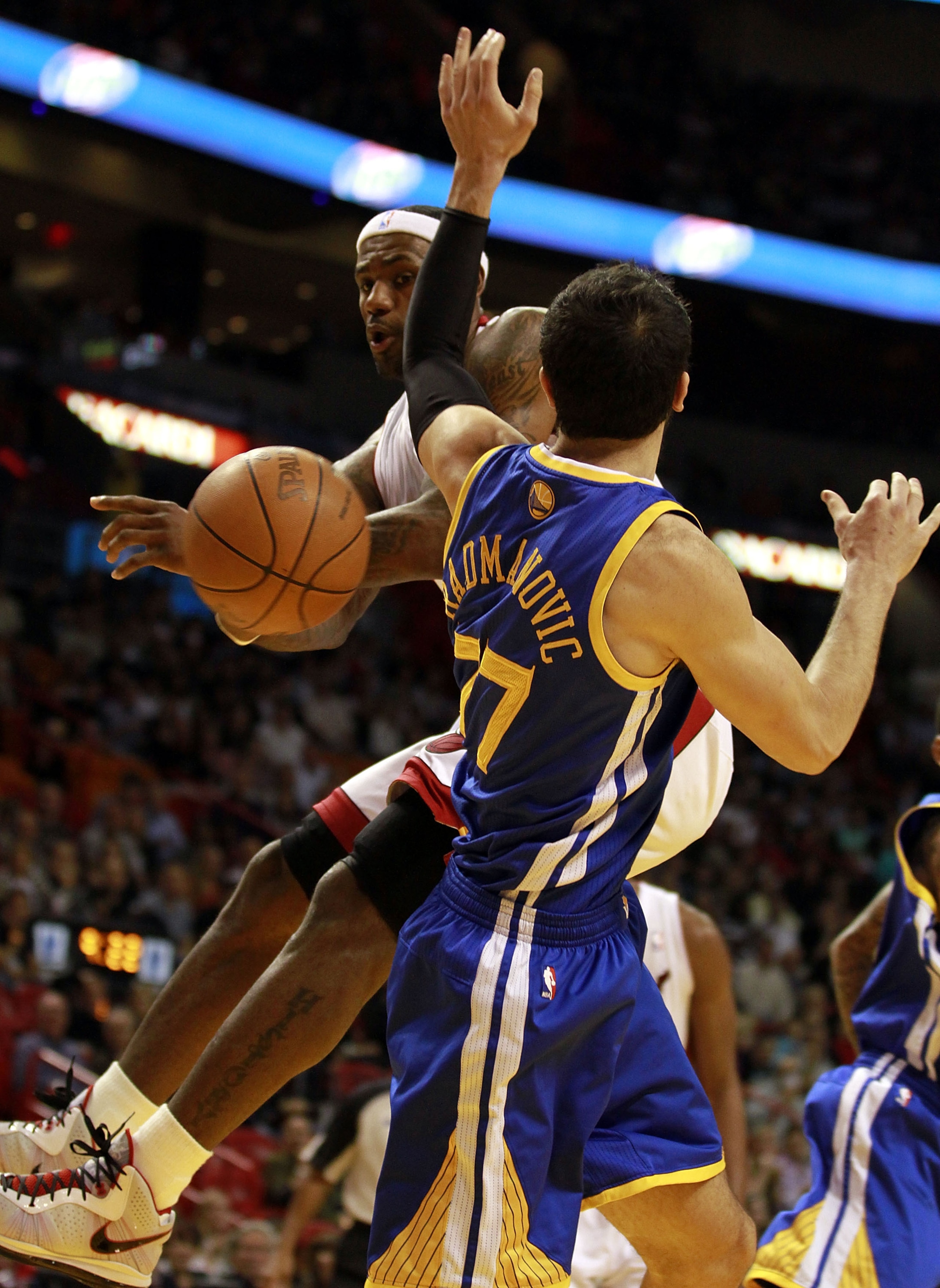 MIAMI, FL - JANUARY 01:  Forward LeBron James #6 of the Miami Heat passes  against Vladimir Radmanovic #77 of the Golden State Warriors at American Airlines Arena on January 1, 2011 in Miami, Florida.  NOTE TO USER: User expressly acknowledges and agrees