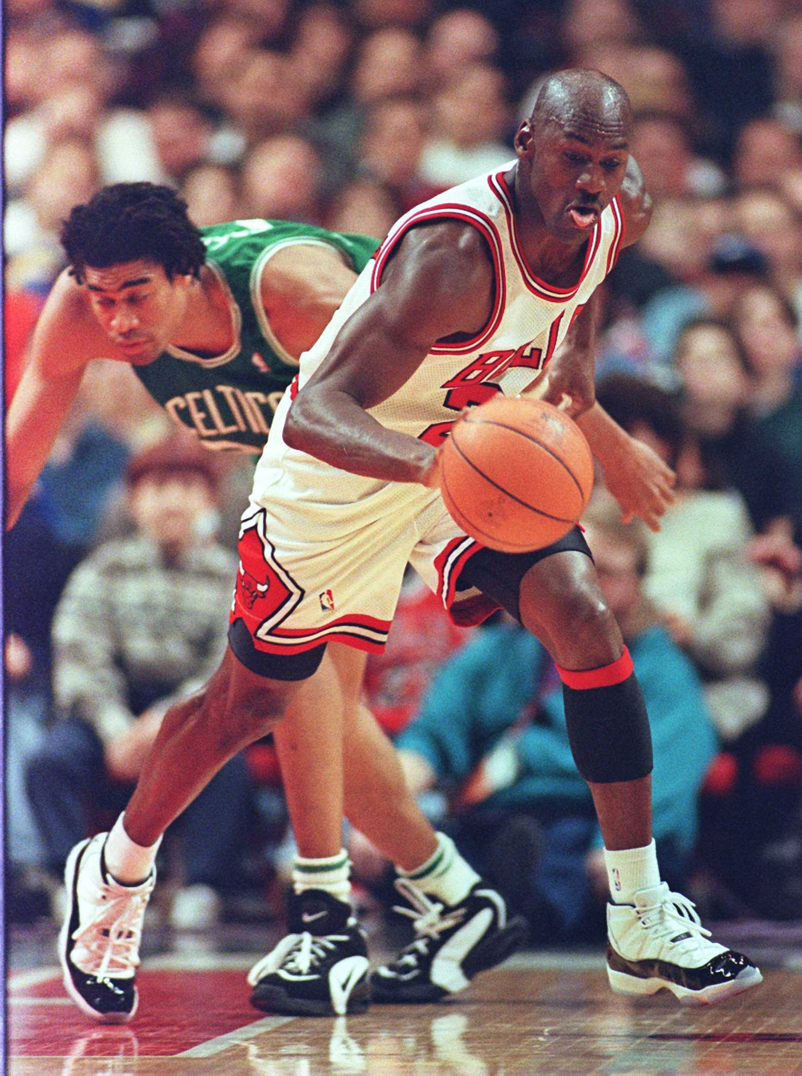 2 Mar 1996:  Guard Michael Jordan of the Chicago Bulls picks up the ball on a defensive rebound and starts running as guard Pervis Ellison of the Boston Celtics stumbles in the first quarter of their game at the United Center in Chicago.  The Bulls enter