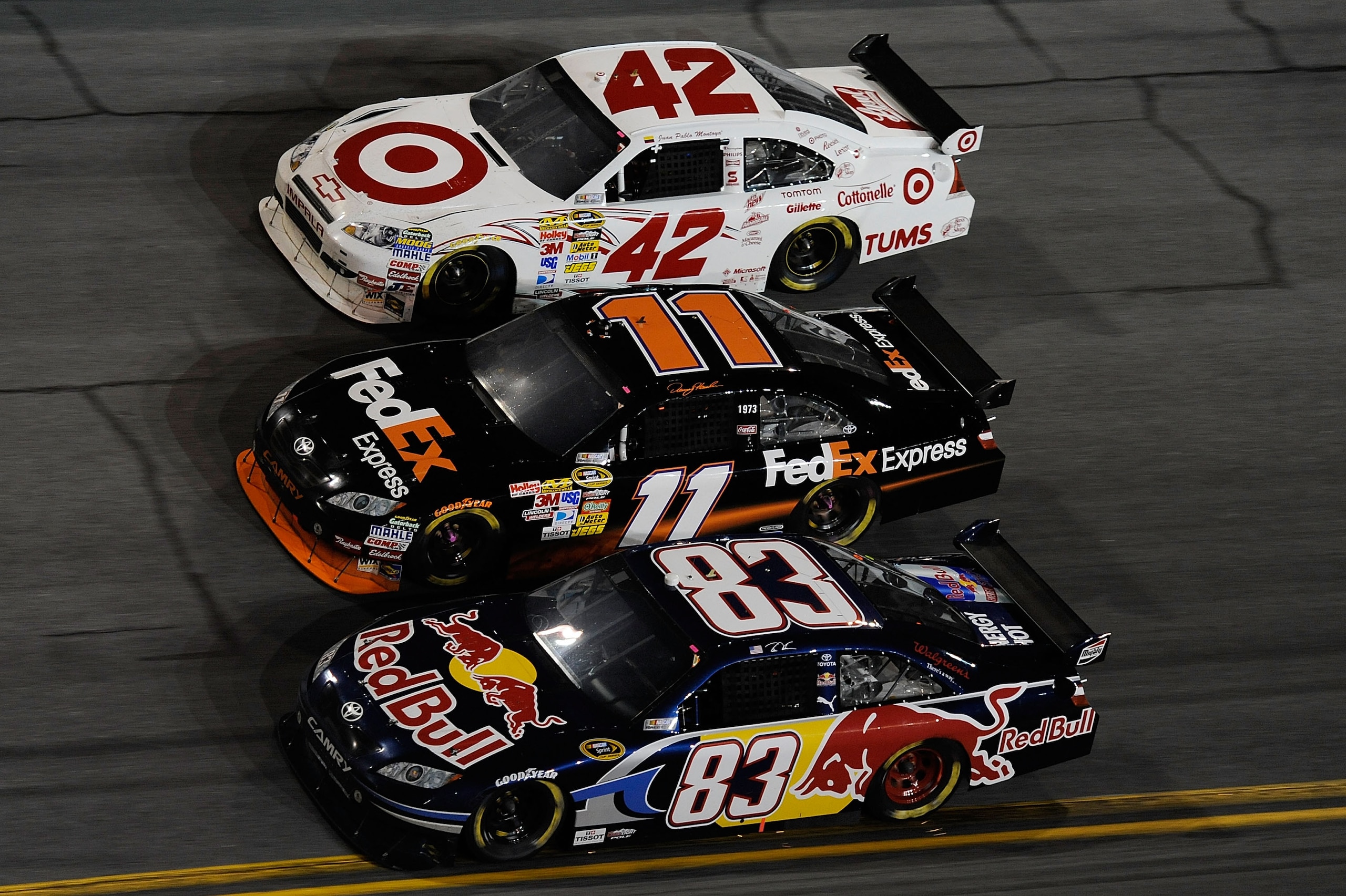 DAYTONA BEACH, FL - FEBRUARY 06:  Brian Vickers, driver of the #83 Red Bull Toyota, Denny Hamlin, driver of the #11 FedEx Toyota, and Juan Pablo Montoya, driver of the #42 Target Chevrolet, race during the Budweiser Shootout at Daytona International Speed