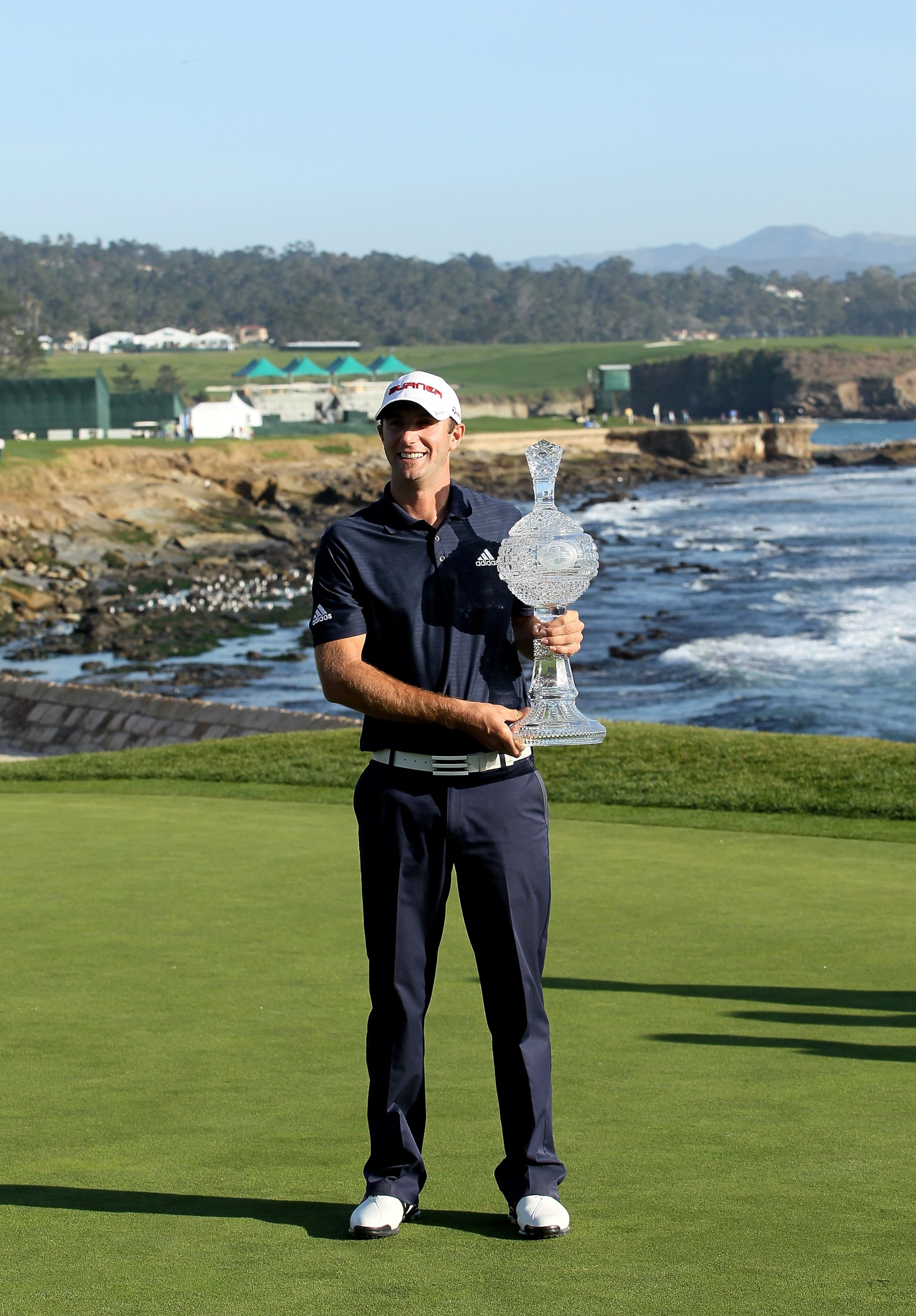 PEBBLE BEACH, CA - FEBRUARY 14:  Dustin Johnson poses with the trophy on the 18th green after the final round of the AT&T Pebble Beach National Pro-Am at Pebble Beach Golf Links on February 14, 2010 in Pebble Beach, California.  (Photo by Stephen Dunn/Get