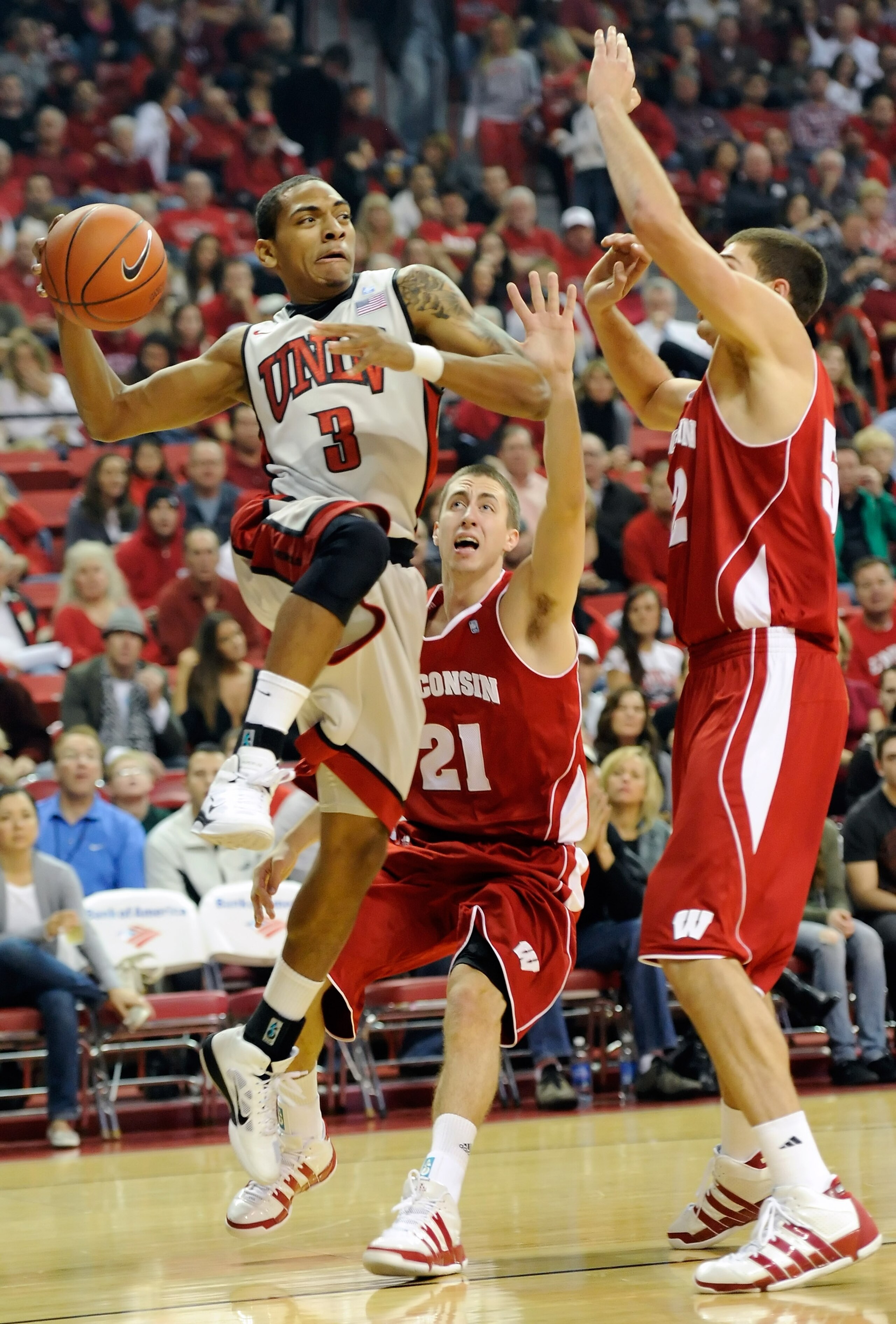 LAS VEGAS - NOVEMBER 20:  Anthony Marshall #3 of the UNLV Rebels passes the ball as Josh Gasser #21 and Keaton Nankivil #52 of the Wisconsin Badgers defend during their game at the Thomas & Mack Center November 20, 2010 in Las Vegas, Nevada. UNLV won 68-6