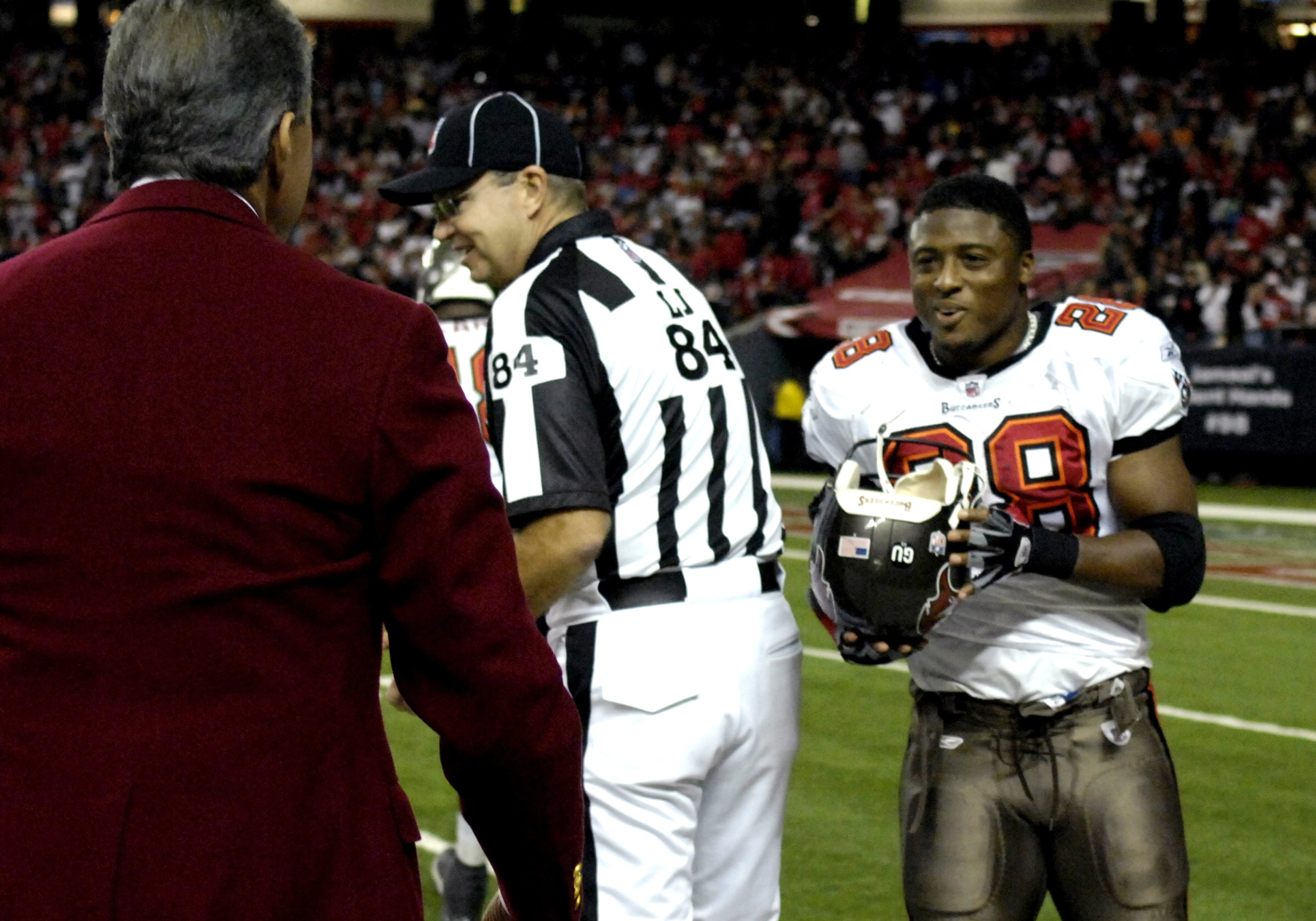 ATLANTA - DECEMBER 14: Onwer Arthur Blank (left) returns the helmet of running back Warrick Dunn #28 of the Tampa Bay Buccaneers at the Georgia Dome on December 14, 2008 in Atlanta, Georgia. Dunn lost his helmet during a tackle on the sidelines near Blank