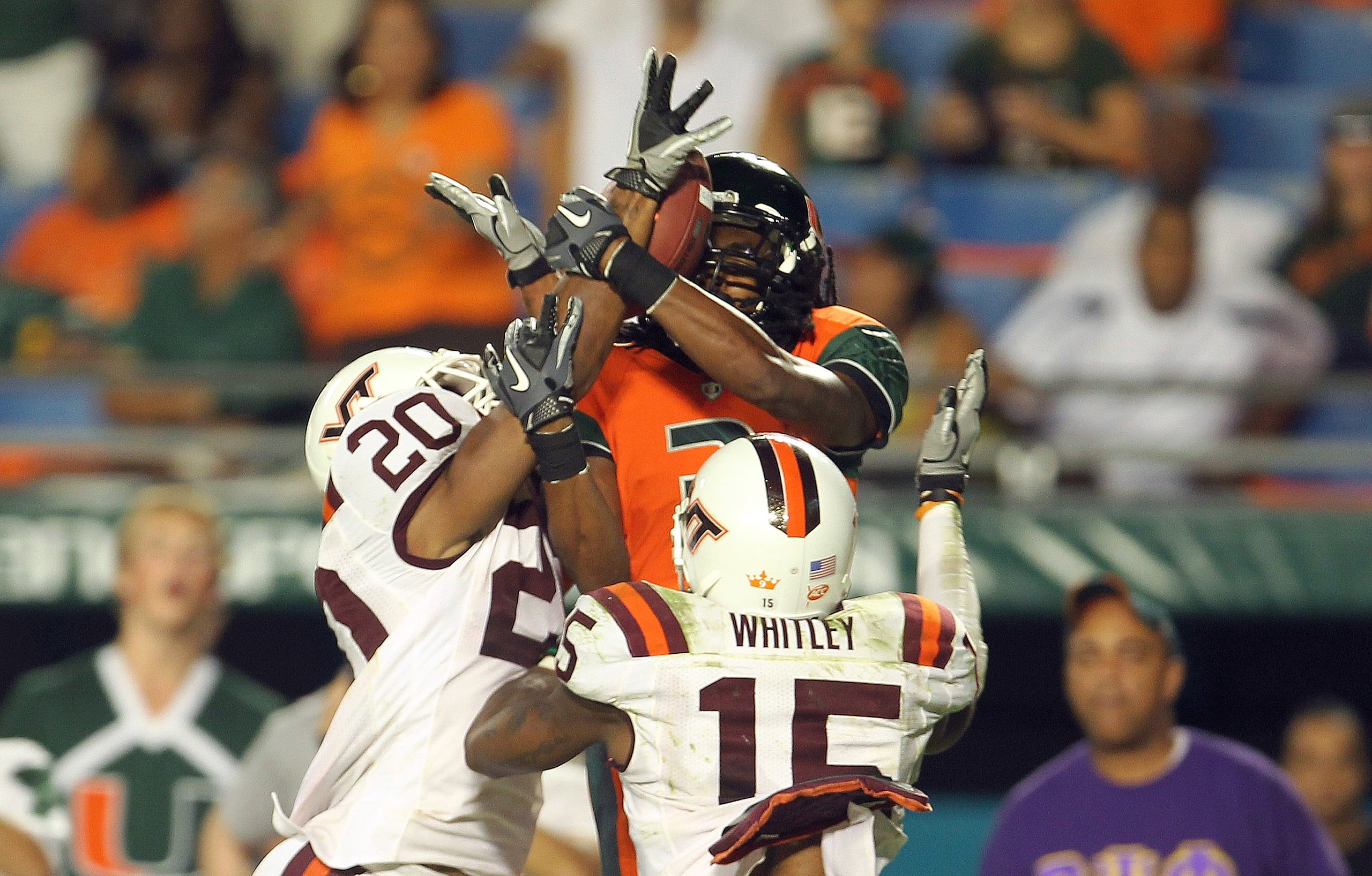 MIAMI - NOVEMBER 20: Travis Benjamin #3 of the Miami Hurricanes goes up for a catch before being interfered with by Eddie Whitley #15 and Jayron Hosley #20 of the Virginia Tech Hokies at Sun Life Stadium on November 20, 2010 in Miami, Florida.  (Photo by