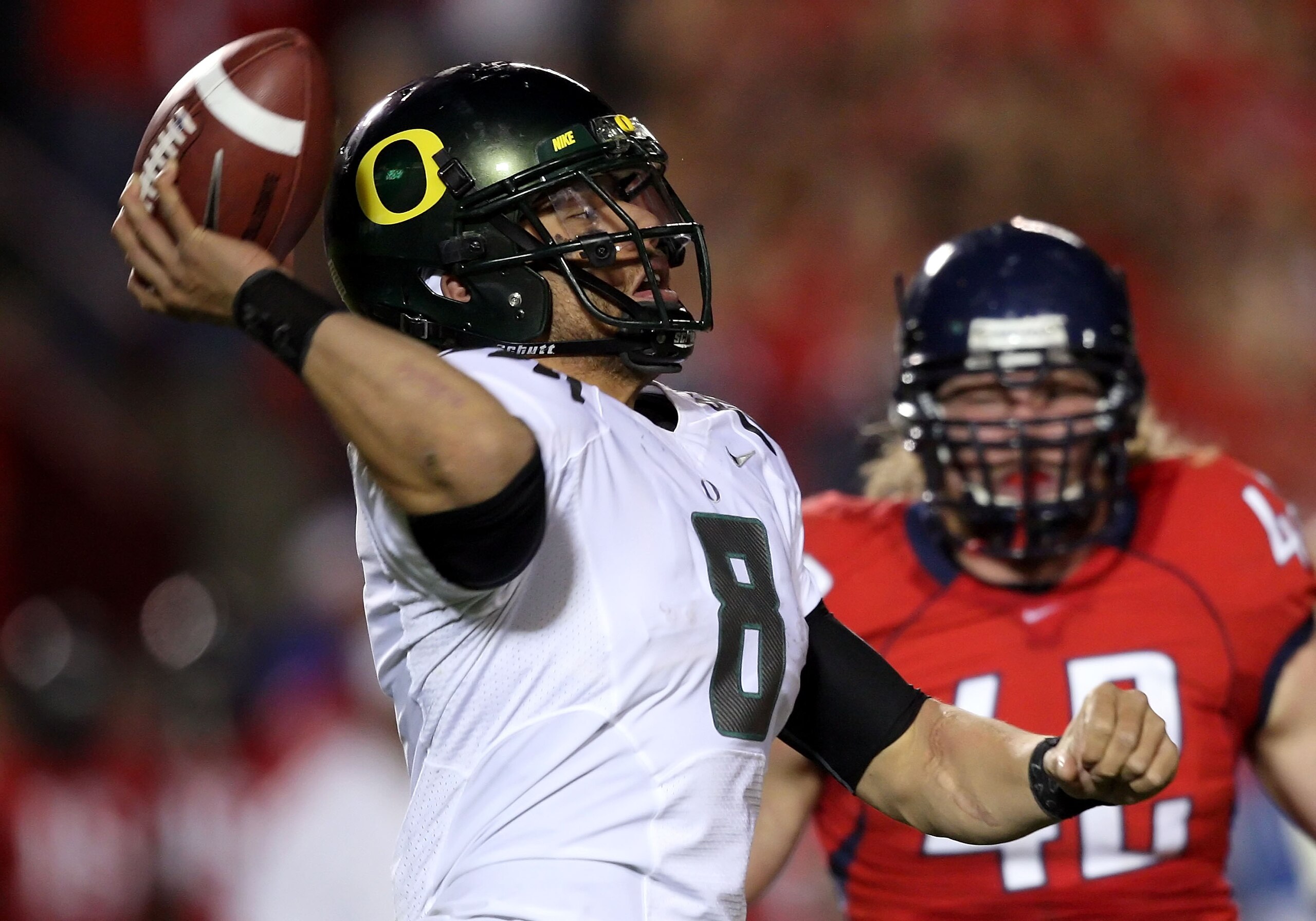 TUCSON, AZ - NOVEMBER 21:  Quarterback Jeremiah Masoli #8 of the Oregon Ducks scrambles to pass under pressure from Brooks Reed #42 of the Arizona Wildcats during the college football game at Arizona Stadium on November 21, 2009 in Tucson, Arizona. The Du
