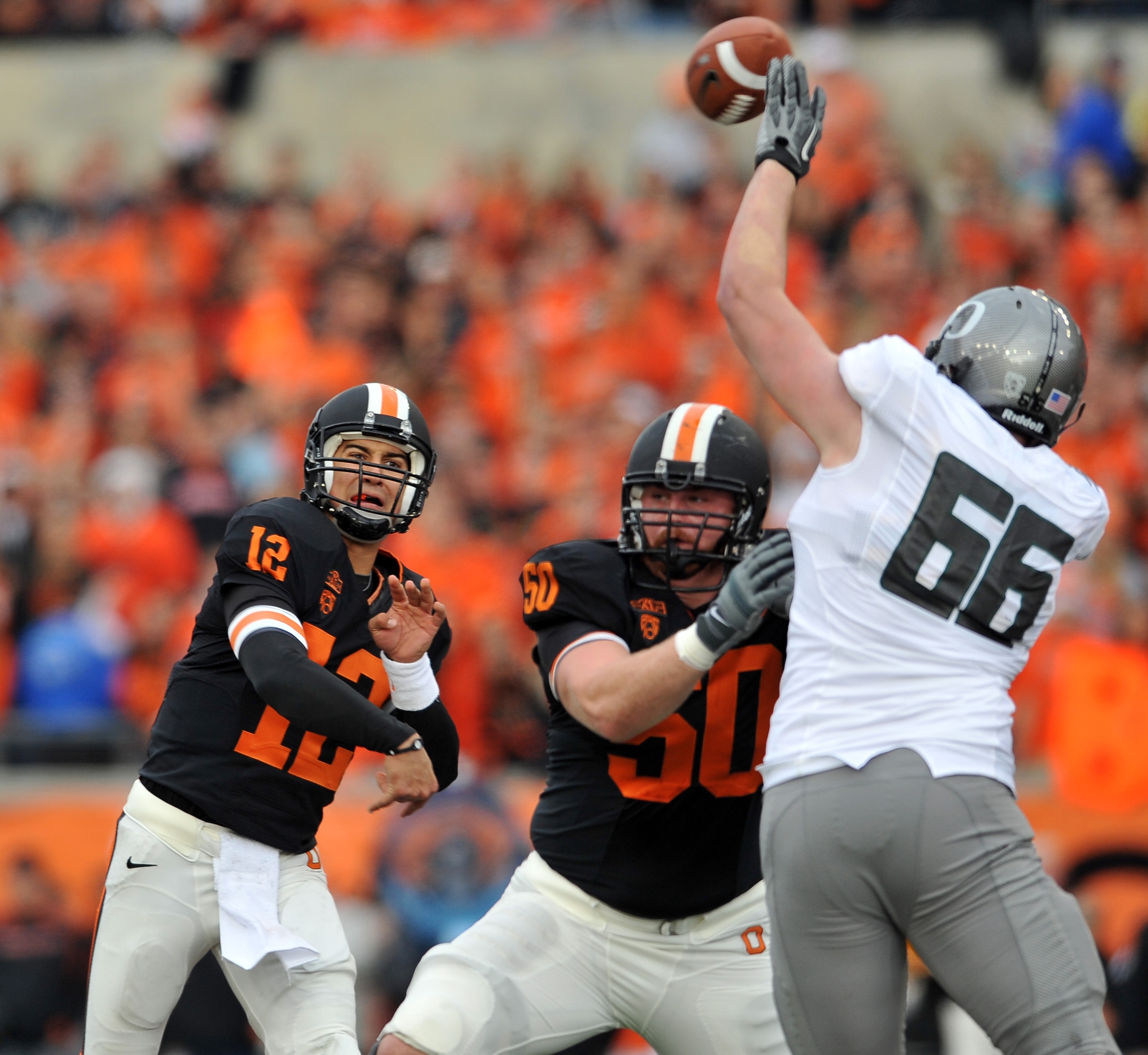 CORVALLIS, OR - DECEMBER 4: Quarterback Ryan Katz #12 of the Oregon State Beavers tries to pass the ball over the outstretched arm of Taylor Hart #66 of the Oregon Ducks in the second quarter the game at Reser Stadium on December 4, 2010 in Corvallis, Ore