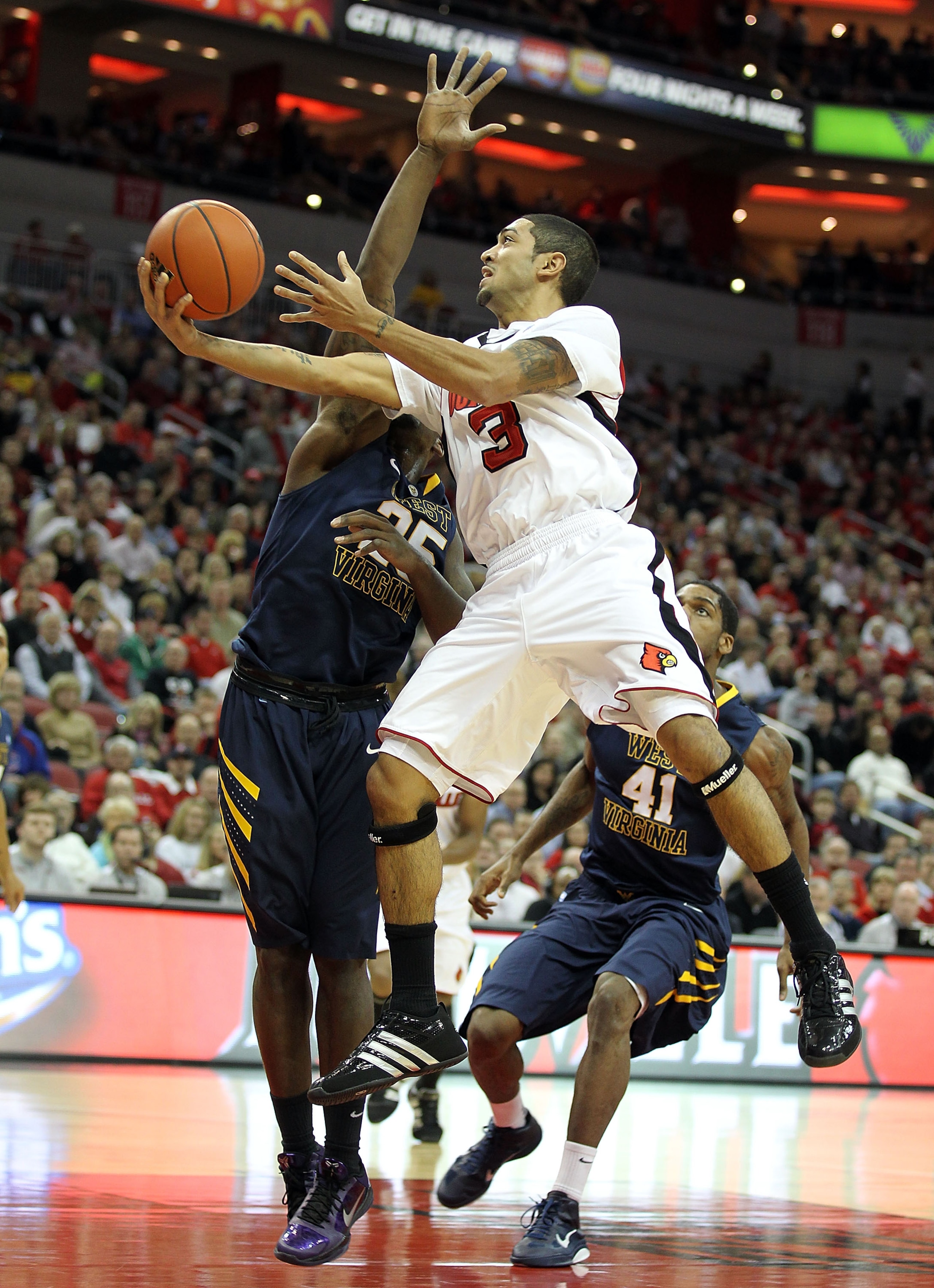 LOUISVILLE, KY - JANUARY 26:  Peyton Siva #3 of the Louisville Cardinals shoots the ball while defended by Darryl Bryant #25 of the West Virginia Mountaineers during the Big East Conference game at the KFC Yum! Center on January 26, 2011 in Louisville, Ke