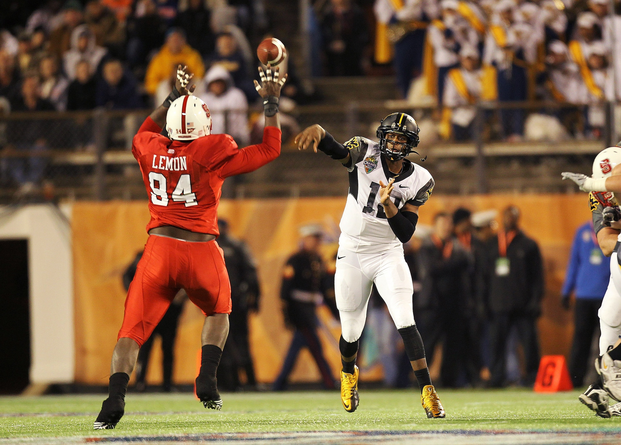 ORLANDO, FL - DECEMBER 28:  Geno Smith #12 of the West Virginia Mountineers passes over George Bryan #84 of the North Carolina State Wolfpack during the Champs Sports Bowl at Florida Citrus Bowl Stadium on December 28, 2010 in Orlando, Florida.  (Photo by