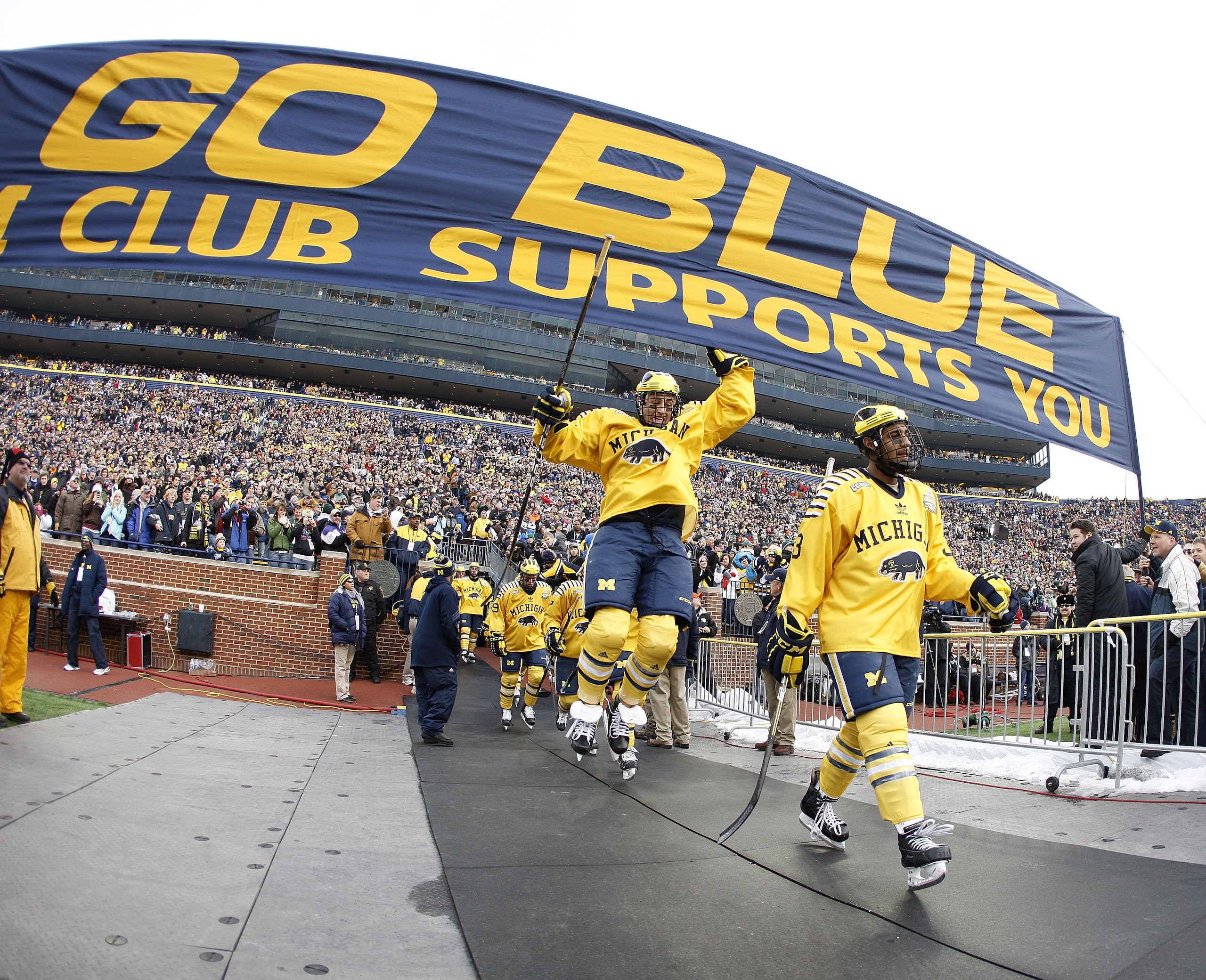 ANN ARBOR, MI - DECEMBER 11:  Lee Moffie #13 of the Michigan Wolverines jumps to the Michigan banner on his way to the ice prior to playing Michigan State at Michigan Stadium on December 11, 2010 in Ann Arbor, Michigan.  (Photo by Gregory Shamus/Getty Ima