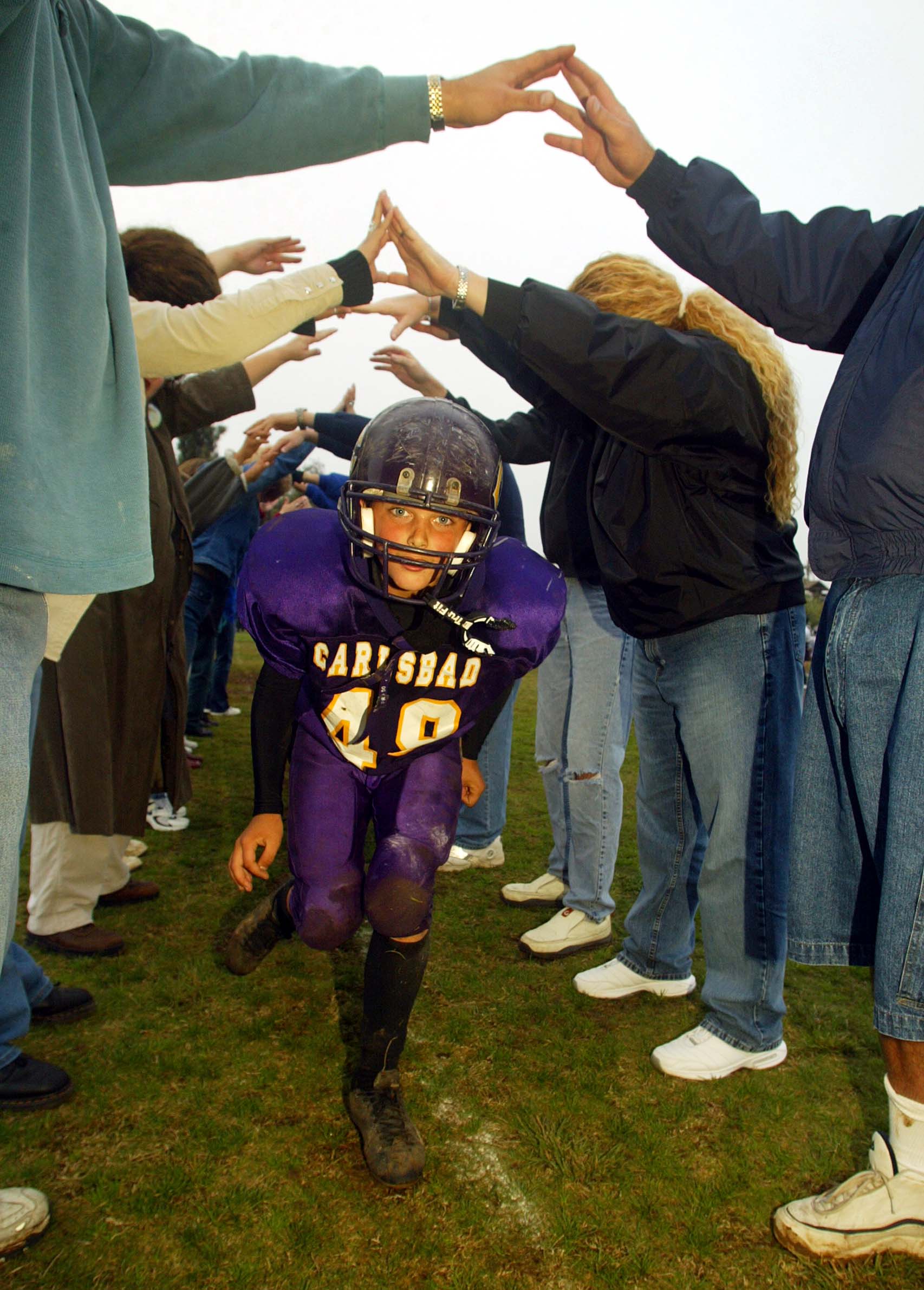 CARLSBAD, CA - NOVEMBER 9:  The Carlsbad Charging Lancers celebrate their 18-0 win over the San Dieguito Ravens by running under their parent's arms during the Pop Warner Division Finals on November 9, 2002 at Carlsbad High School, in Carlsbad, California