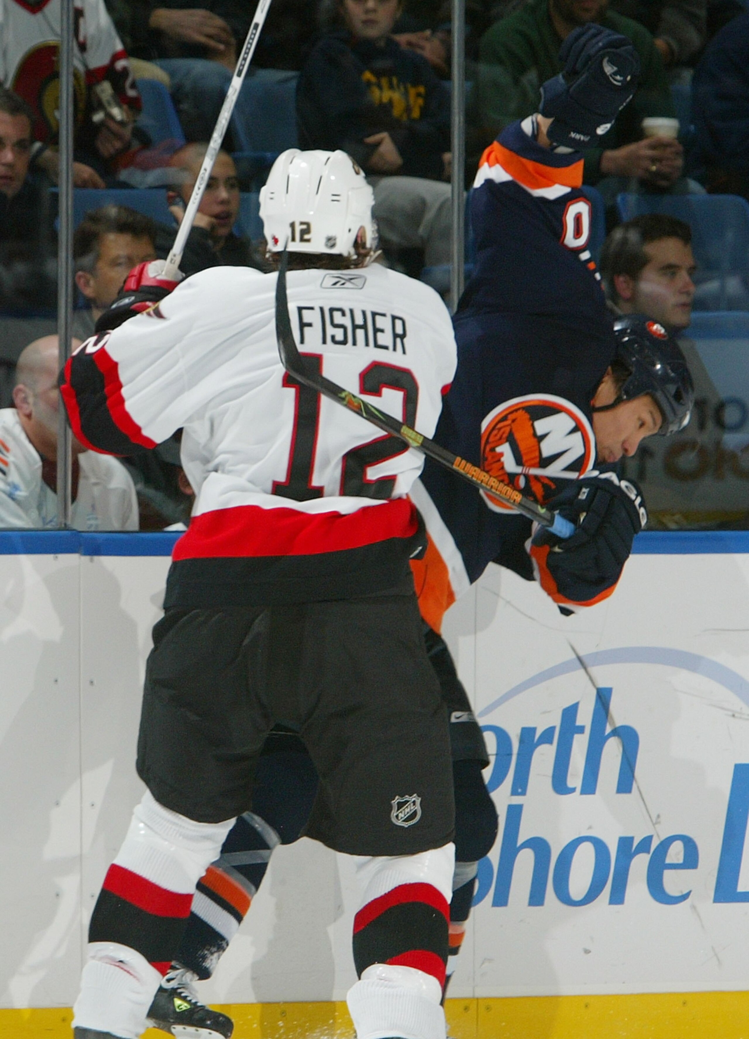 UNIONDALE, NY - DECEMBER 05:  Mike Fisher #12 of the Ottawa Senators checks Richard Park #10  of the New York Islanders against the boards during a NHL game December 5, 2006 at Nassau Coliseum in Uniondale, New York.  (Photo by Jim McIsaac/Getty Images)