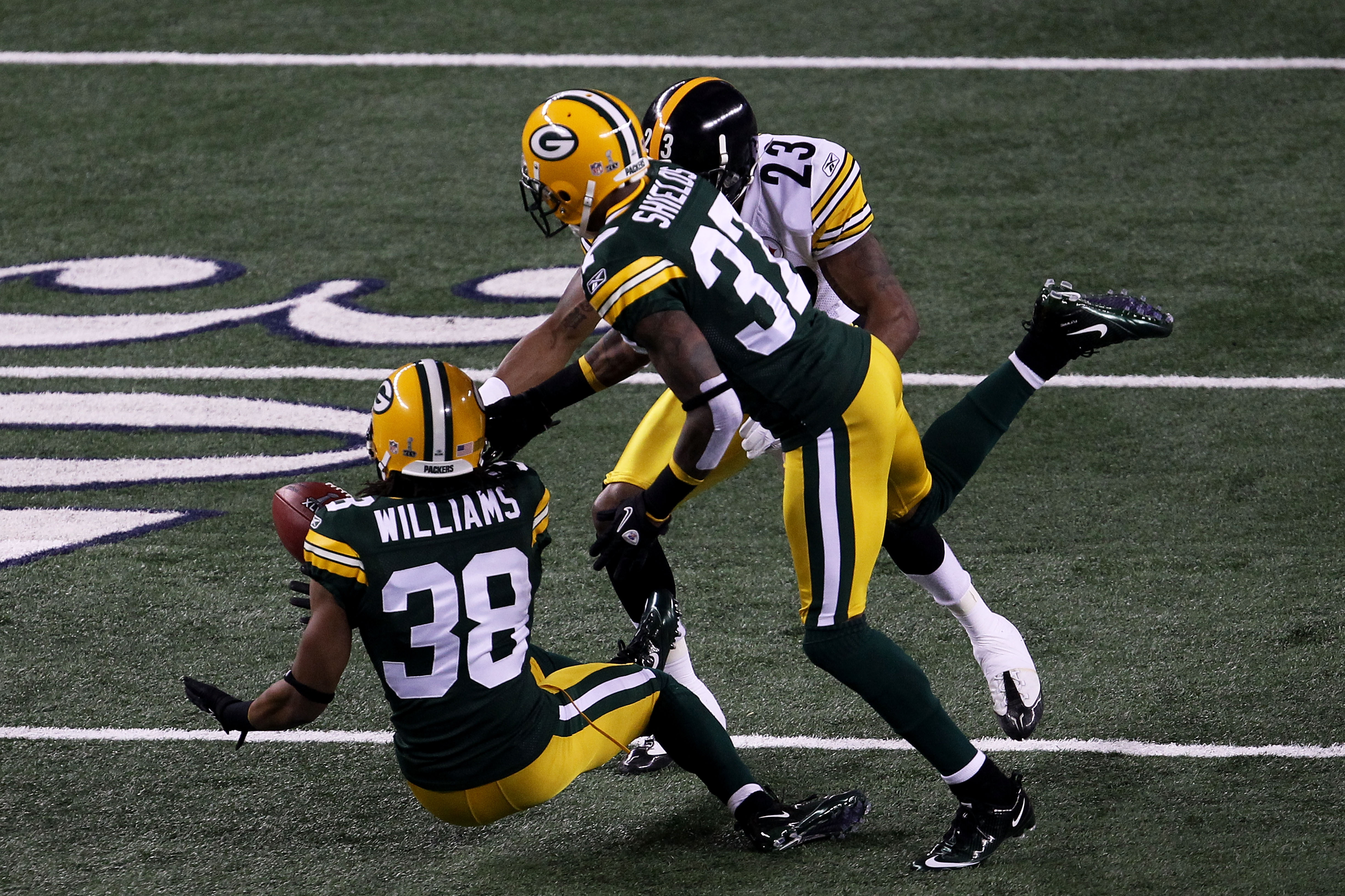ARLINGTON, TX - FEBRUARY 06:  Tramon Williams #38 of the Green Bay Packers muffs a punt as Sam Shields #37 and Keenan Lewis #23 of the Pittsburgh Steelers attempt to recover during Super Bowl XLV at Cowboys Stadium on February 6, 2011 in Arlington, Texas.