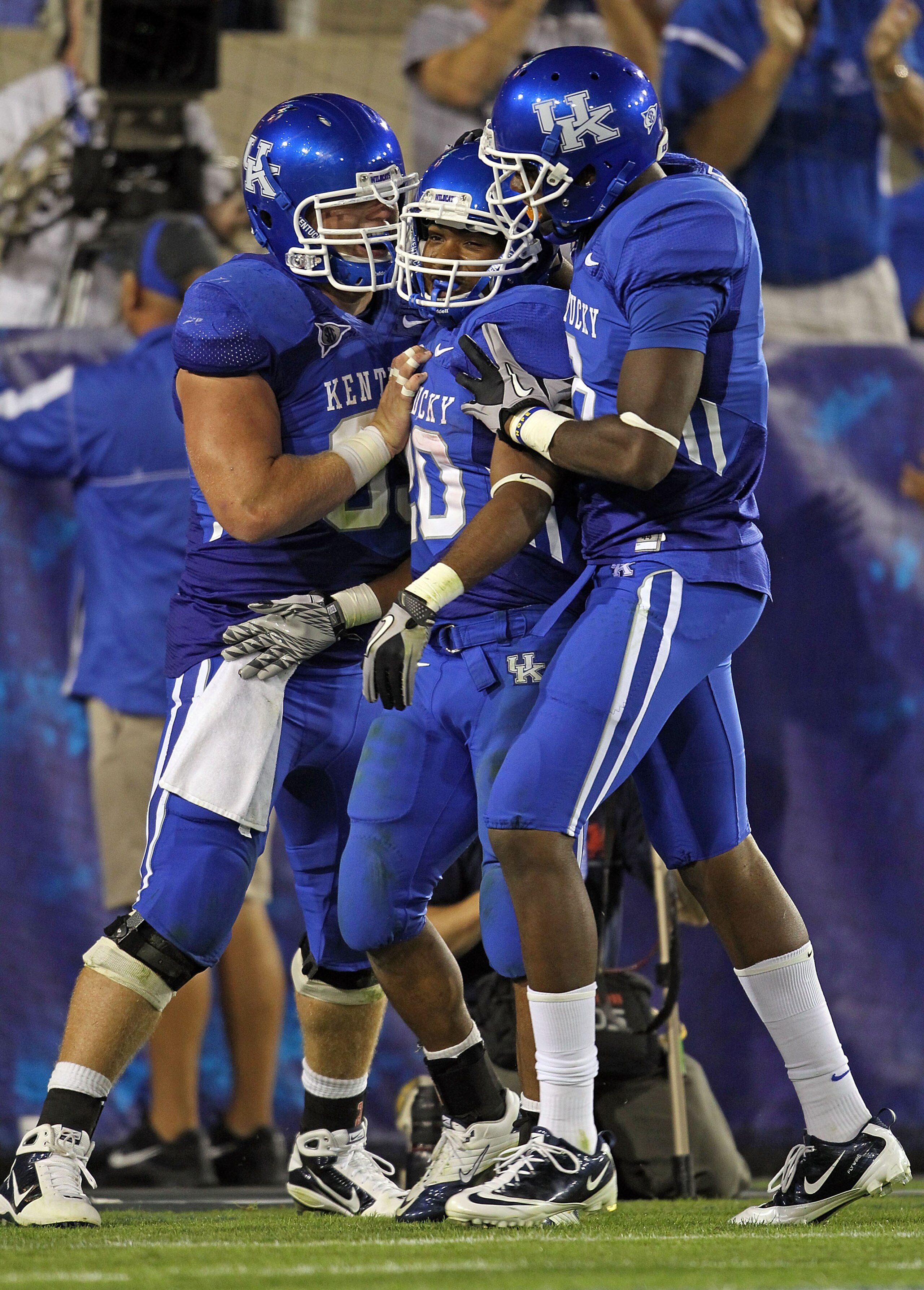 LEXINGTON, KY - SEPTEMBER 18:  Matt Smith #69 (left) and Chris Matthews #8 (right) of the Kentucky Wildcats celebrate with Derrick Locke #20 (center) after Locke ran for a touchdown during the game against the Akron Zips at Commonwealth Stadium on Septemb