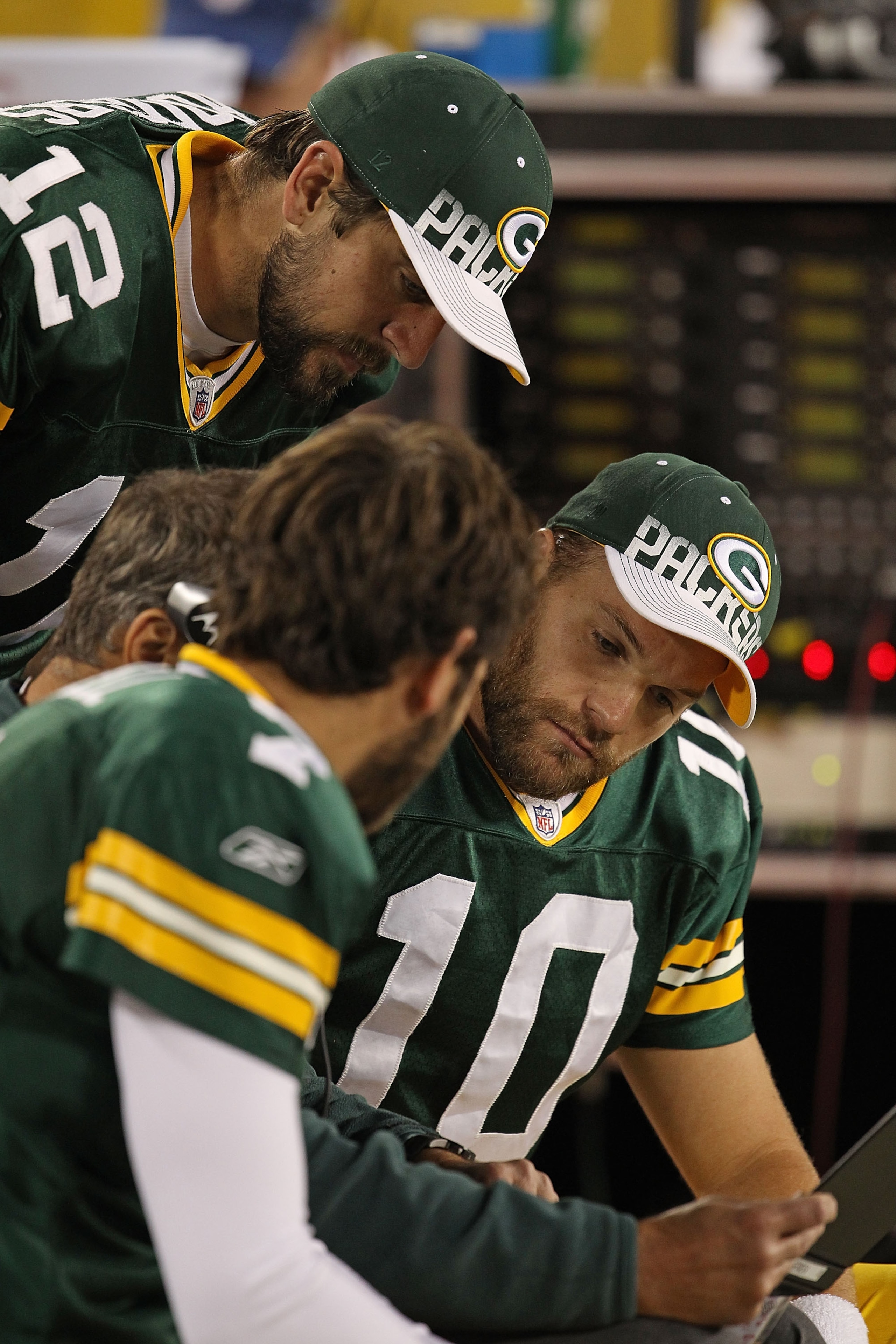 GREEN BAY, WI - AUGUST 26: (L-R) Graham Harrell #7, Aaron Rodgers #12 and Matt Flynn #10 of the Green Bay Packers look over plays on the bench during a preseason game against the Indianapolis Colts at Lambeau Field on August 26, 2010 in Green Bay, Wiscons