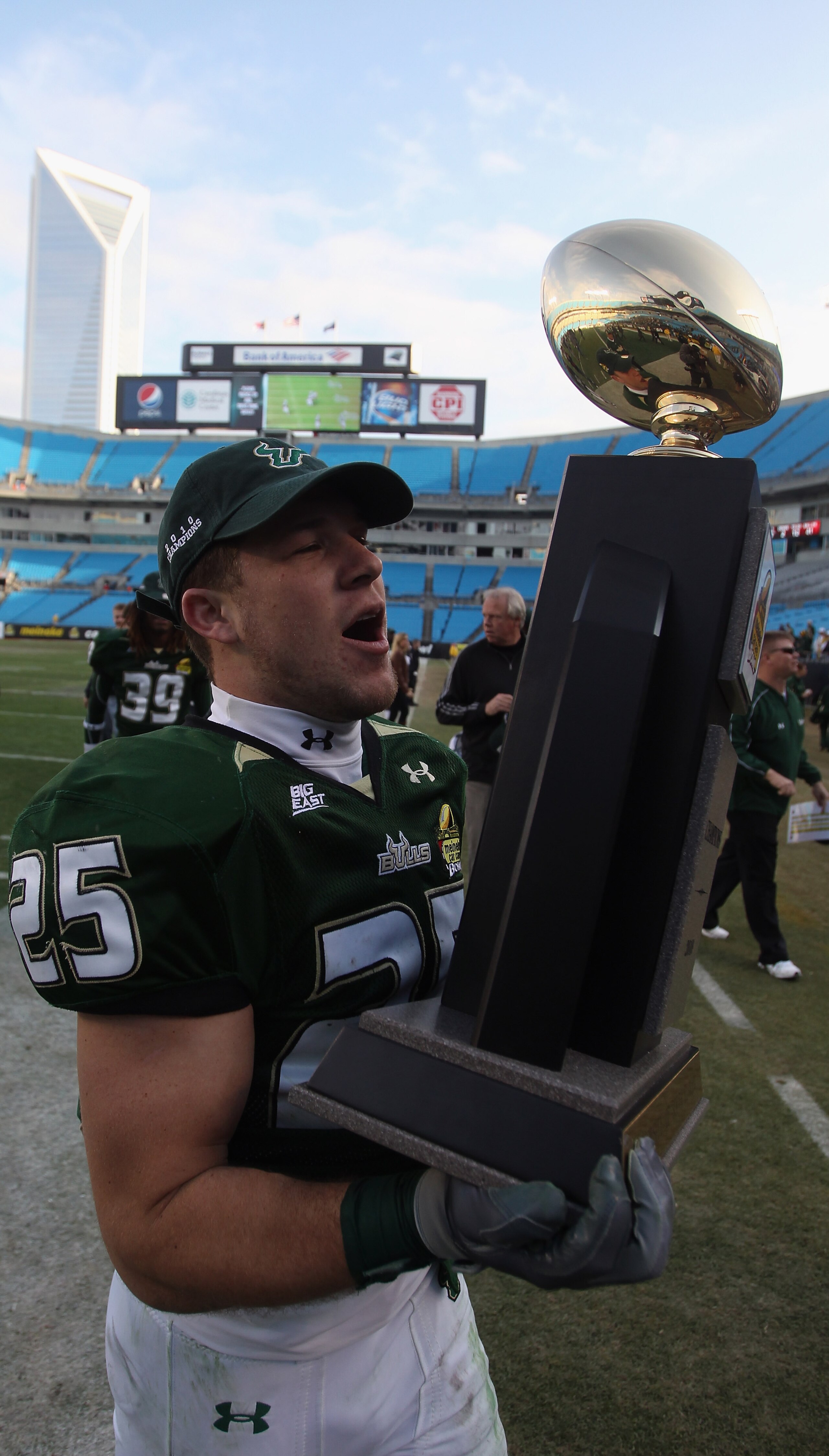 CHARLOTTE, NC - DECEMBER 31:  Joel Miller #25 of the USF Bulls runs off the field with the trophy after a 31-26 victory over the Clemson Tigers during their game at Bank of America Stadium on December 31, 2010 in Charlotte, North Carolina.  (Photo by Stre