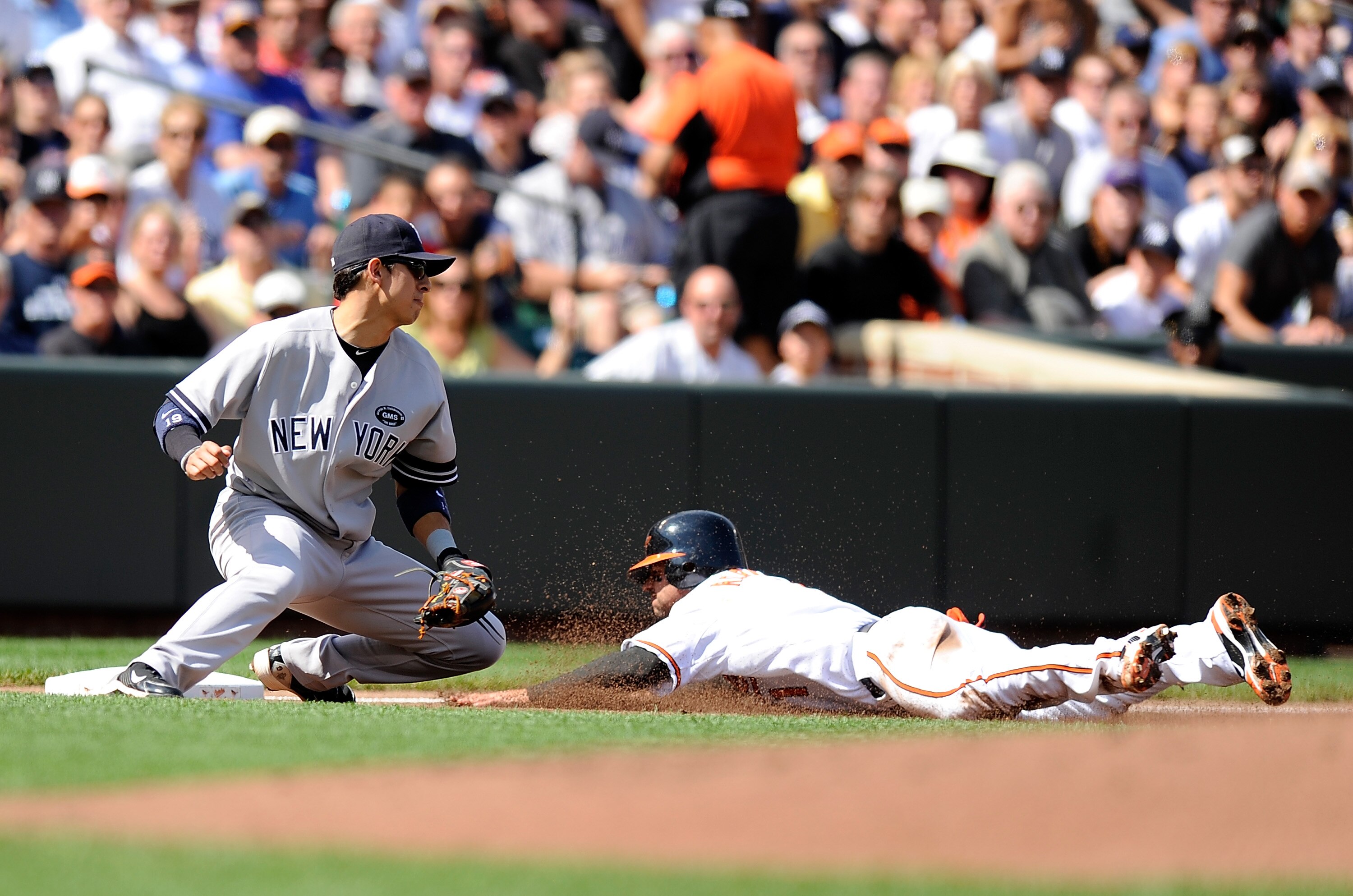 BALTIMORE - SEPTEMBER 19:  Brian Roberts #1 of the Baltimore Orioles slides safely into third base ahead of the tag of Ramiro Pena #19 of the New York Yankees at Camden Yards on September 19, 2010 in Baltimore, Maryland.  (Photo by Greg Fiume/Getty Images