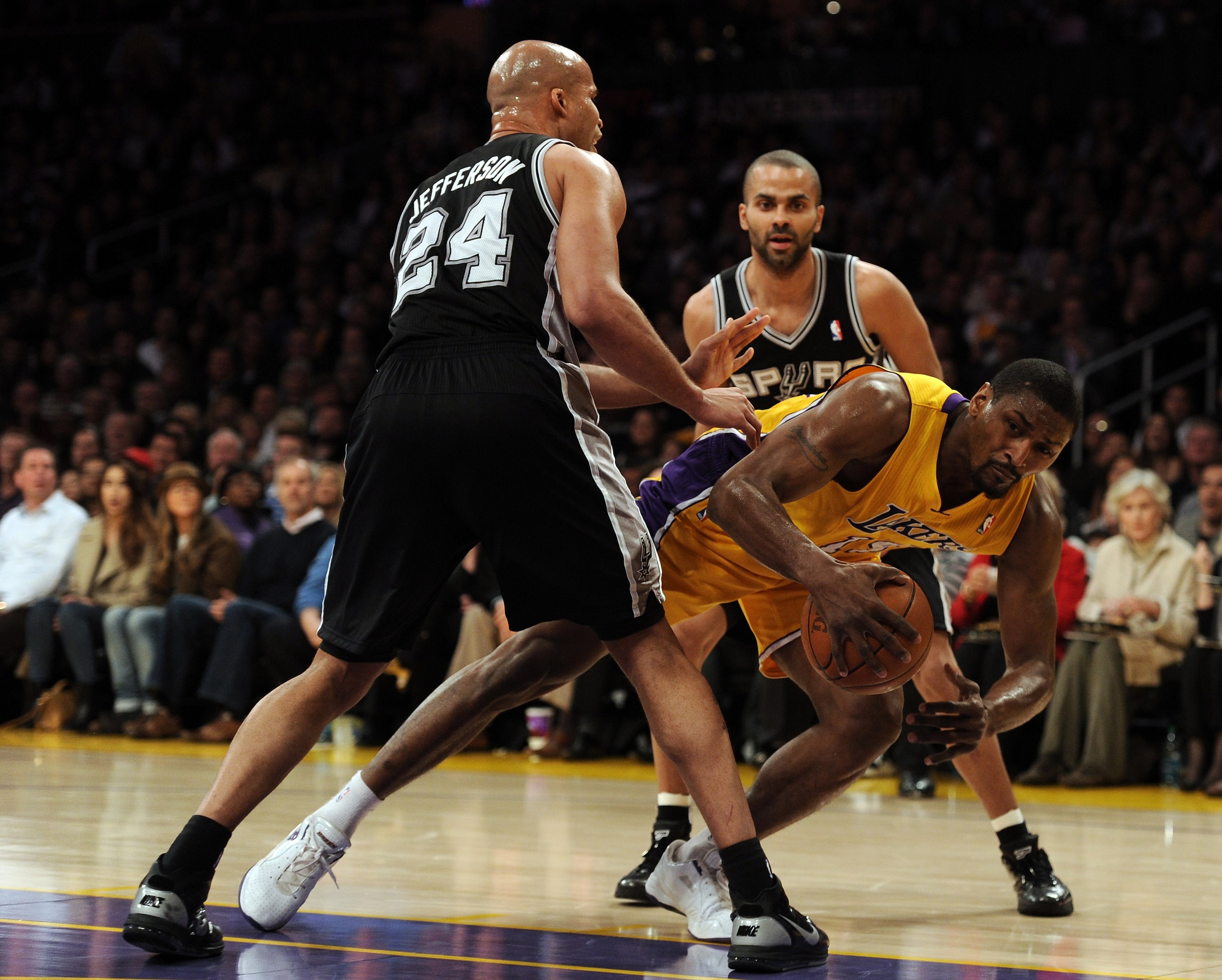 LOS ANGELES, CA - FEBRUARY 03:  Ron Artest #15 of the Los Angeles Lakers loses his footing as he is guarded by Richard Jefferson #24 and Tony Parker #9 of the San Antonio Spurs at Staples Center on February 3, 2011 in Los Angeles, California.  NOTE TO USE