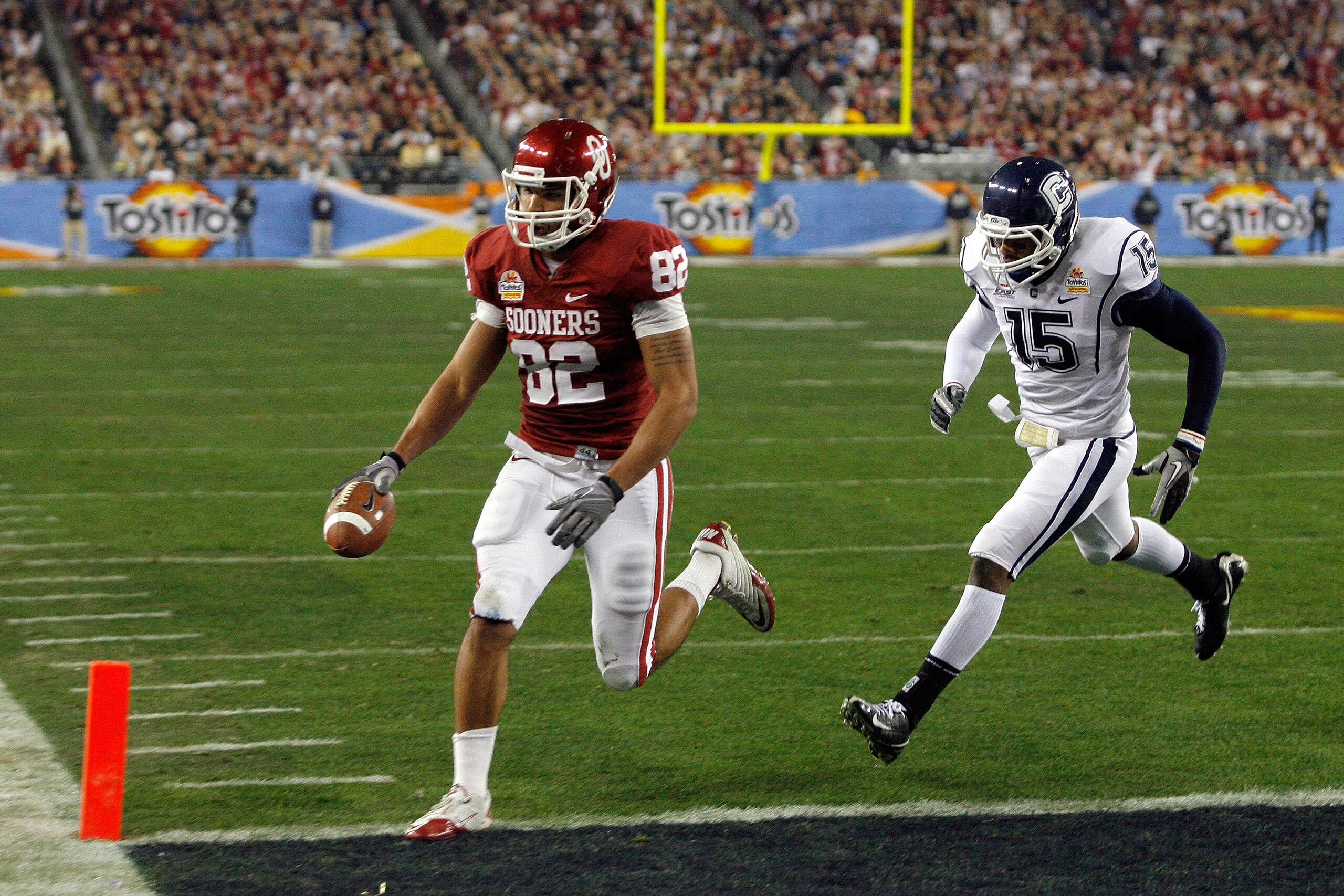 GLENDALE, AZ - JANUARY 01:  Tight end James Hanna #82 of the Oklahoma Sooners catches a touchdown pass in the first quarter past Jerome Junior #15 of the Connecticut Huskies during the Tostitos Fiesta Bowl at the Universtity of Phoenix Stadium on January