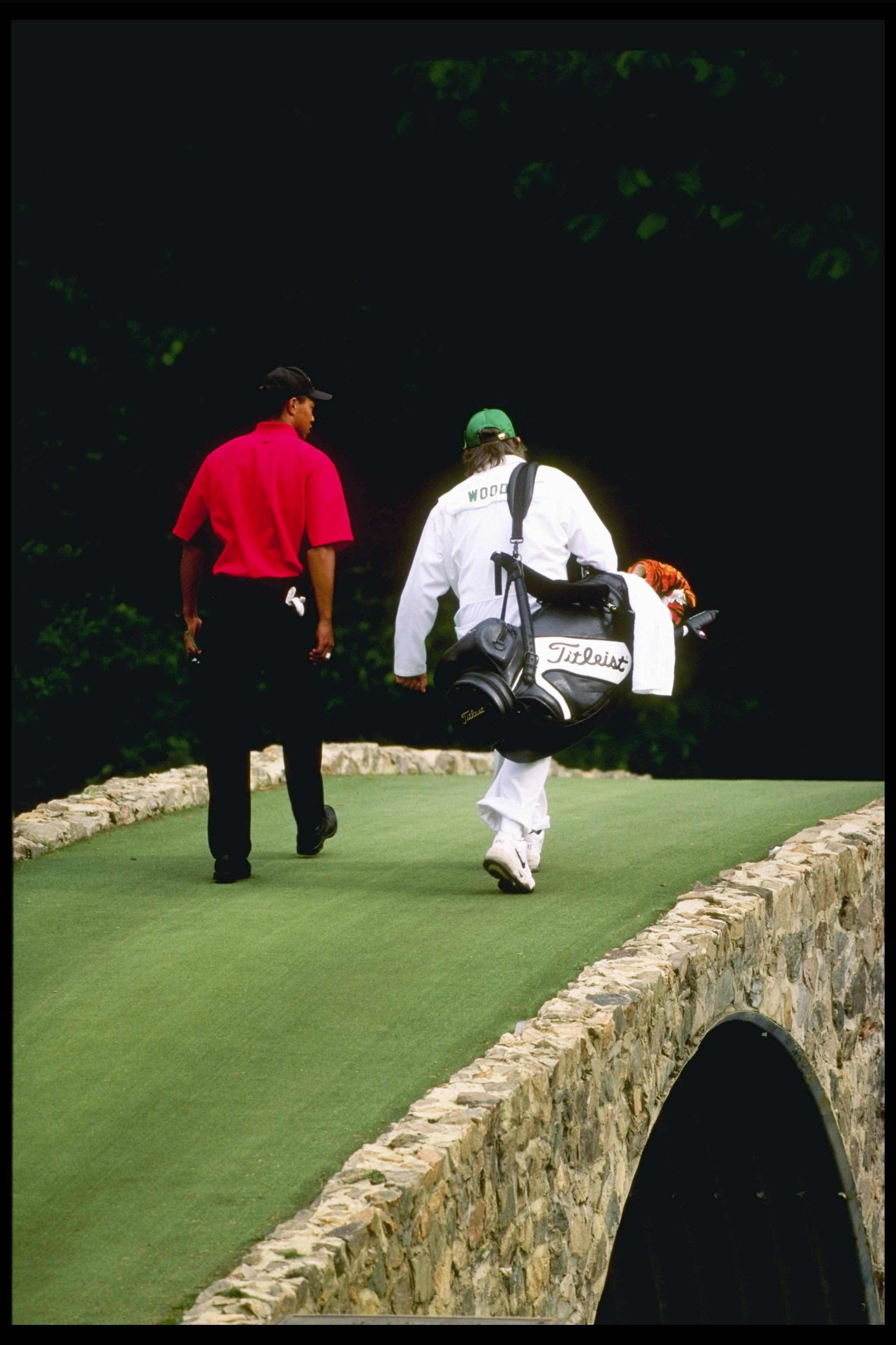 13 Apr 1997: Tigers Woods walks with his caddie Mike Cowan across Hogan''s Bridge on the 12th hole at the Masters at the Augusta National Golf Course in Augusta, Georgia.