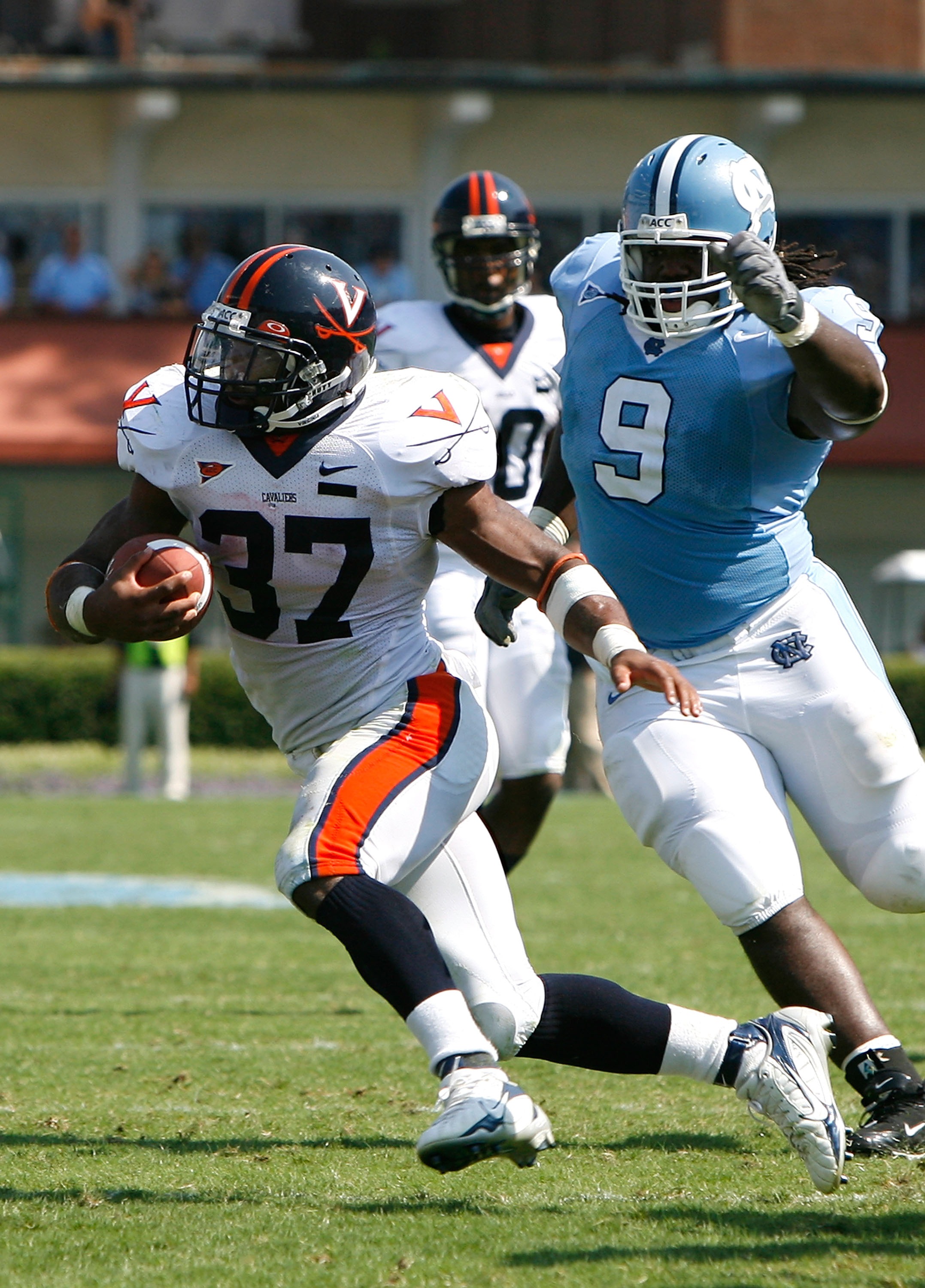 CHAPEL HILL, NC - SEPTEMBER 15:  Tailback Cedric Peerman #37 of the Virginia Cavaliers rushes away from defensive tackle Marvin Austin #9 of the North Carolina Tar Heels during the Cavaliers 22-20 win in their Atlantic Coast Conference football game at Ke