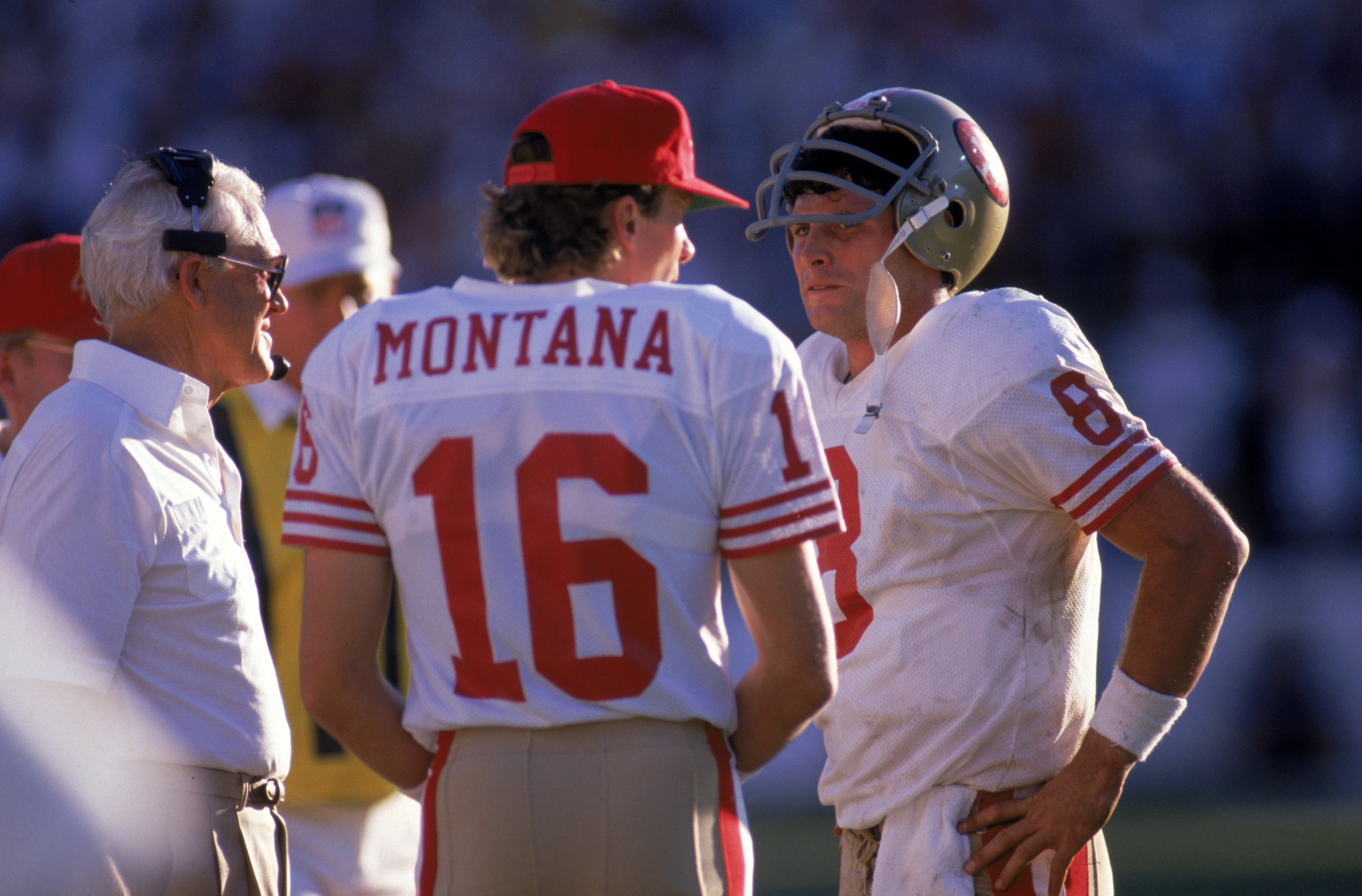 TEMPE, AZ - NOVEMBER 6:  Quarterbacks Steve Young #8 and Joe Montana #16 of the San Francisco 49ers discuss strategy with head coach Bill Walsh during the game against the Phoenix Cardinals at Sun Devil Stadium on Novemer 6, 1988 in Tempe, Arizona.  The C