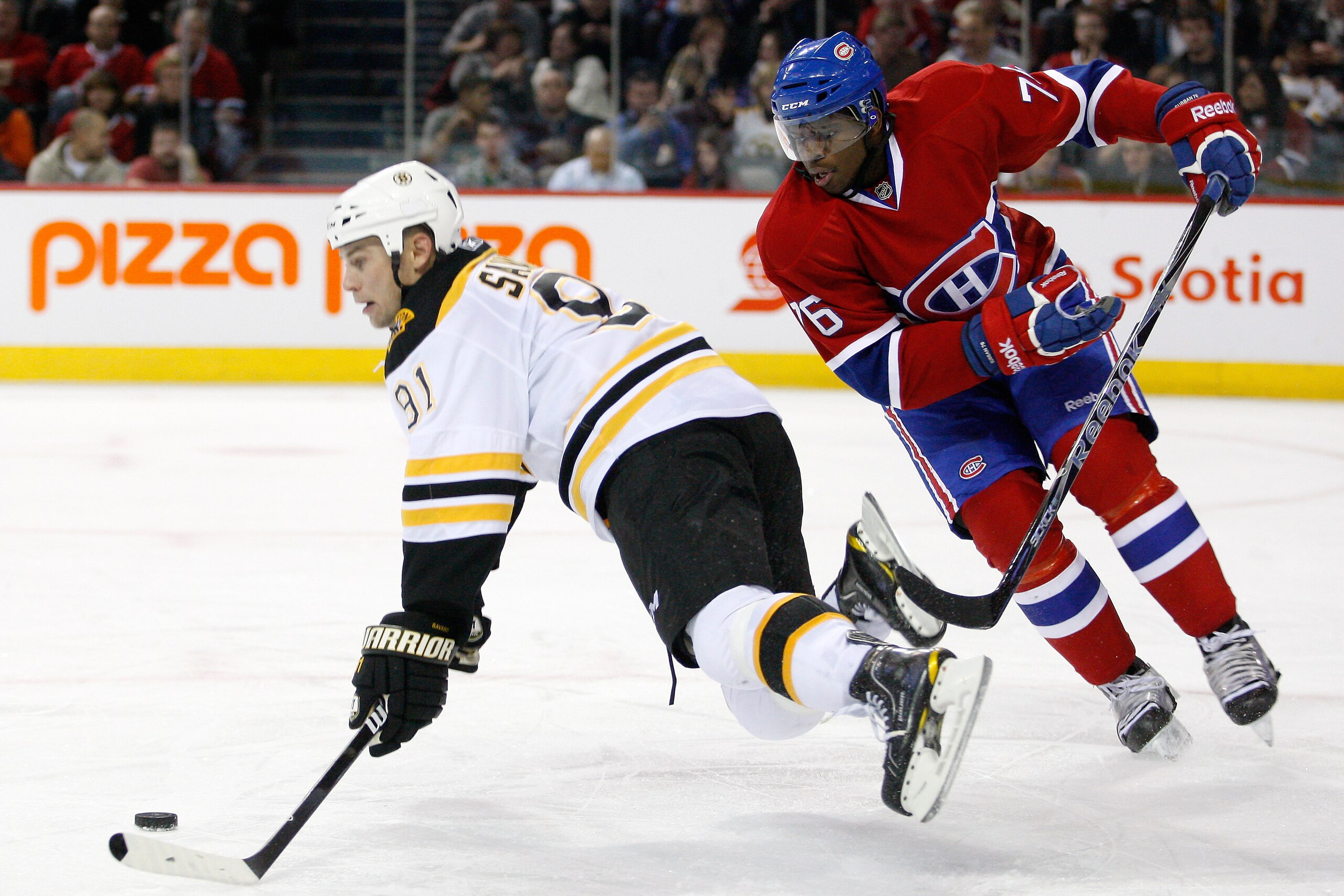 MONTREAL, CANADA - DECEMBER 16:  P.K. Subban #76 of the Montreal Canadiens trips Marc Savard #91 of the Boston Bruins during the NHL game at the Bell Centre on December 16, 2010 in Montreal, Quebec, Canada.  The Canadiens defeated the Bruins 4-3.  (Photo