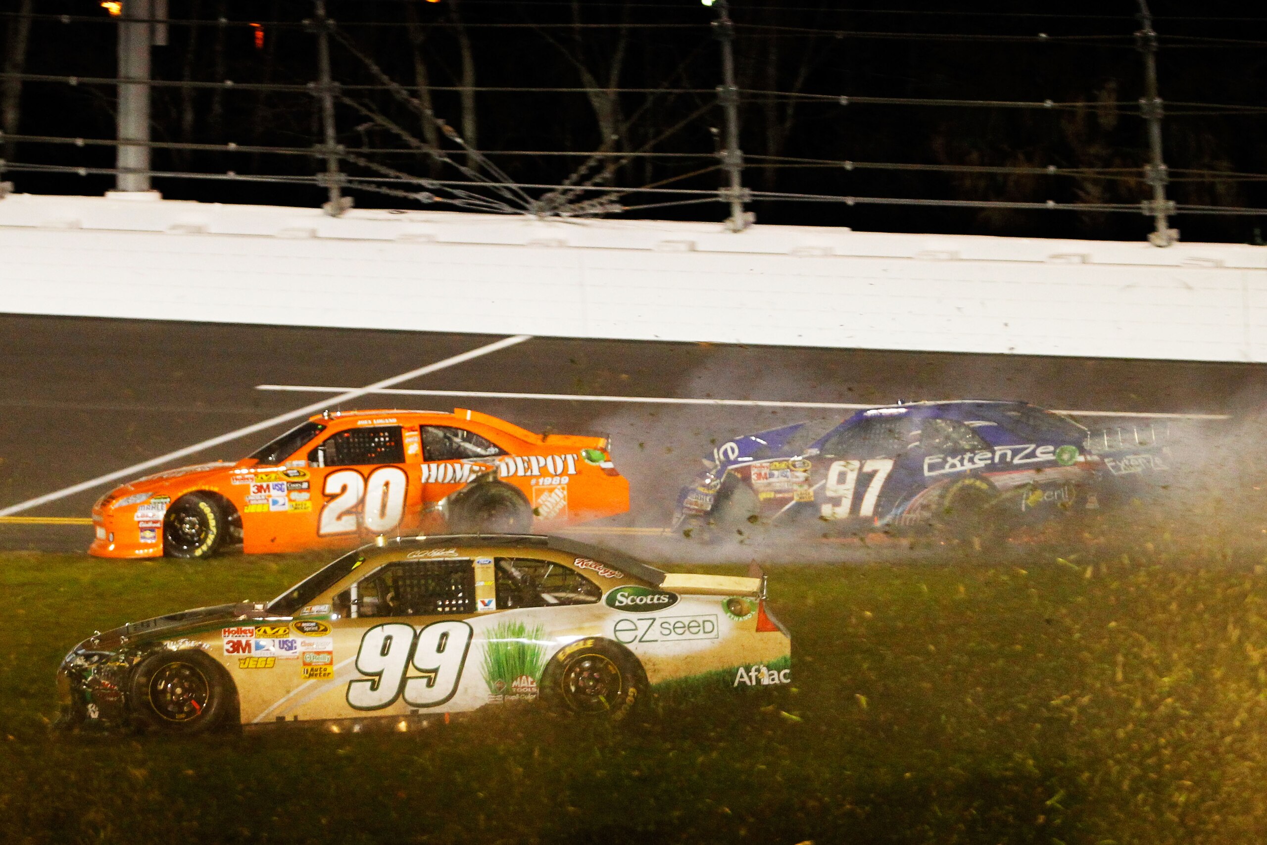 DAYTONA BEACH, FL - FEBRUARY 12:  Carl Edwards, driver of the #99 Scotts Ford, drives through the grass after crashing with Joey Logano, driver of the #20 Home Depot Toyota, and Kevin Conway, driver of the #97 ExtenZe Toyota, during the NASCAR Budweiser S
