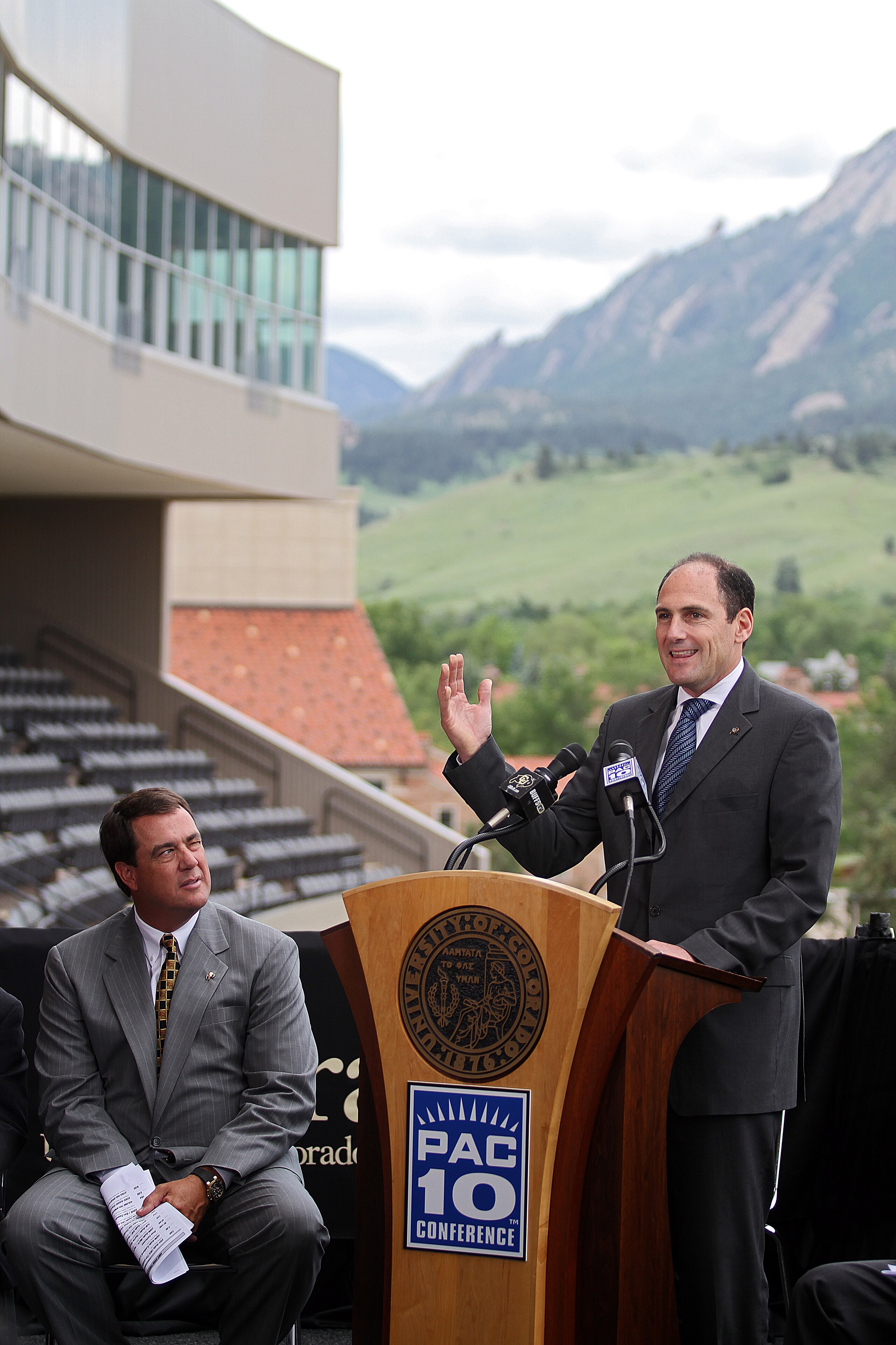 BOULDER, CO - JUNE 11:  University of Colorado Athletic Director Mike Bohn (L) listens as  PAC-10 Commissioner Larry Scott speaks during a press conference at Folsom Stadium on June 11, 2010 in Boulder, Colorado. The University of Colorado Board of Regent