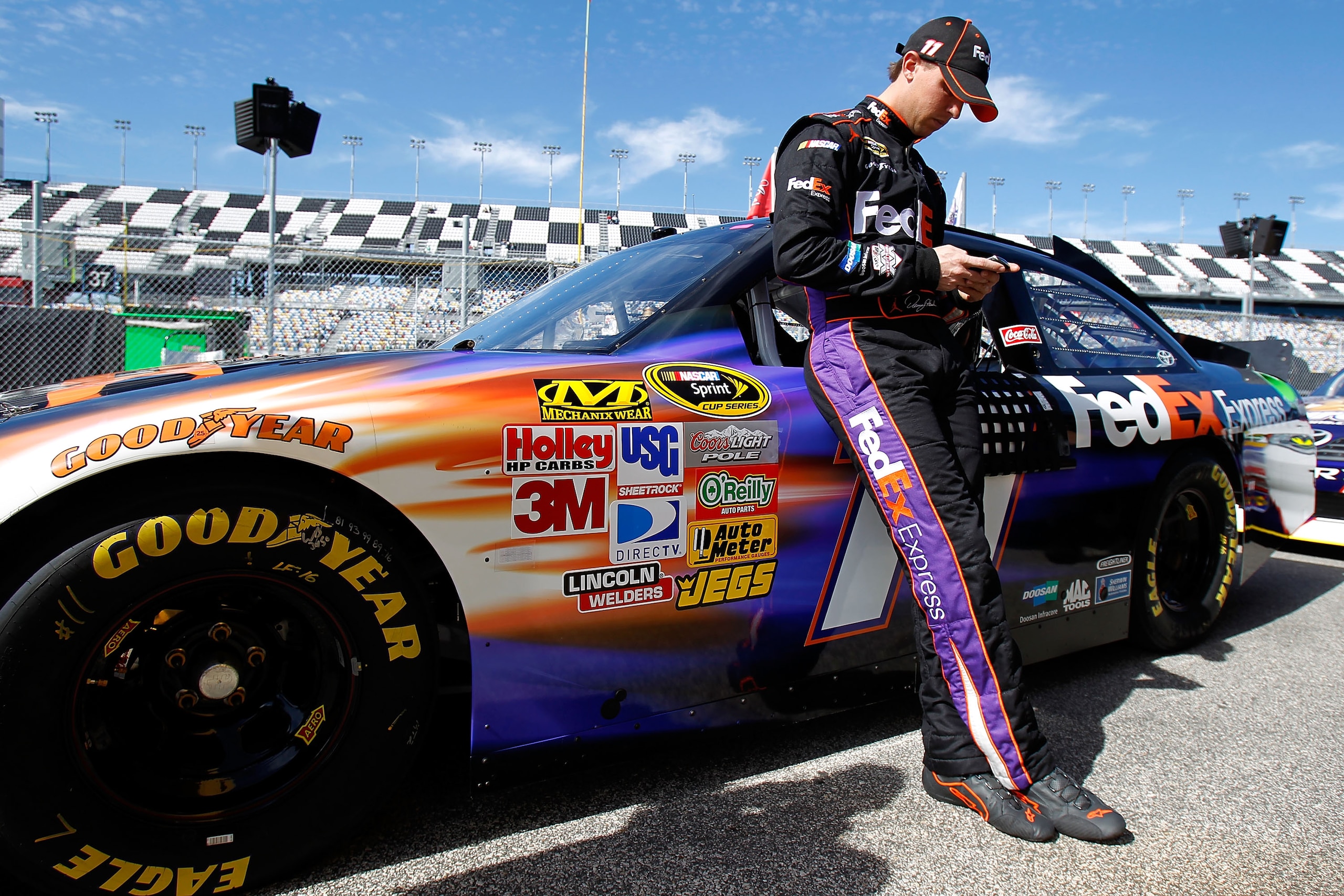 DAYTONA BEACH, FL - FEBRUARY 12: Denny Hamlin, driver of the #11 FedEx Toyota, leans against his car in the garage area during practice for the NASCAR Sprint Cup Series Daytona 500 at Daytona International Speedway on February 12, 2011 in Daytona Beach, DAYTONA BEACH, FL - FEBRUARY 12: Denny Hamlin, driver of the #11 FedEx Toyota, leans against his car in the garage area during practice for the NASCAR Sprint Cup Series Daytona 500 at Daytona International Speedway on February 12, 2011 in Daytona Beach,