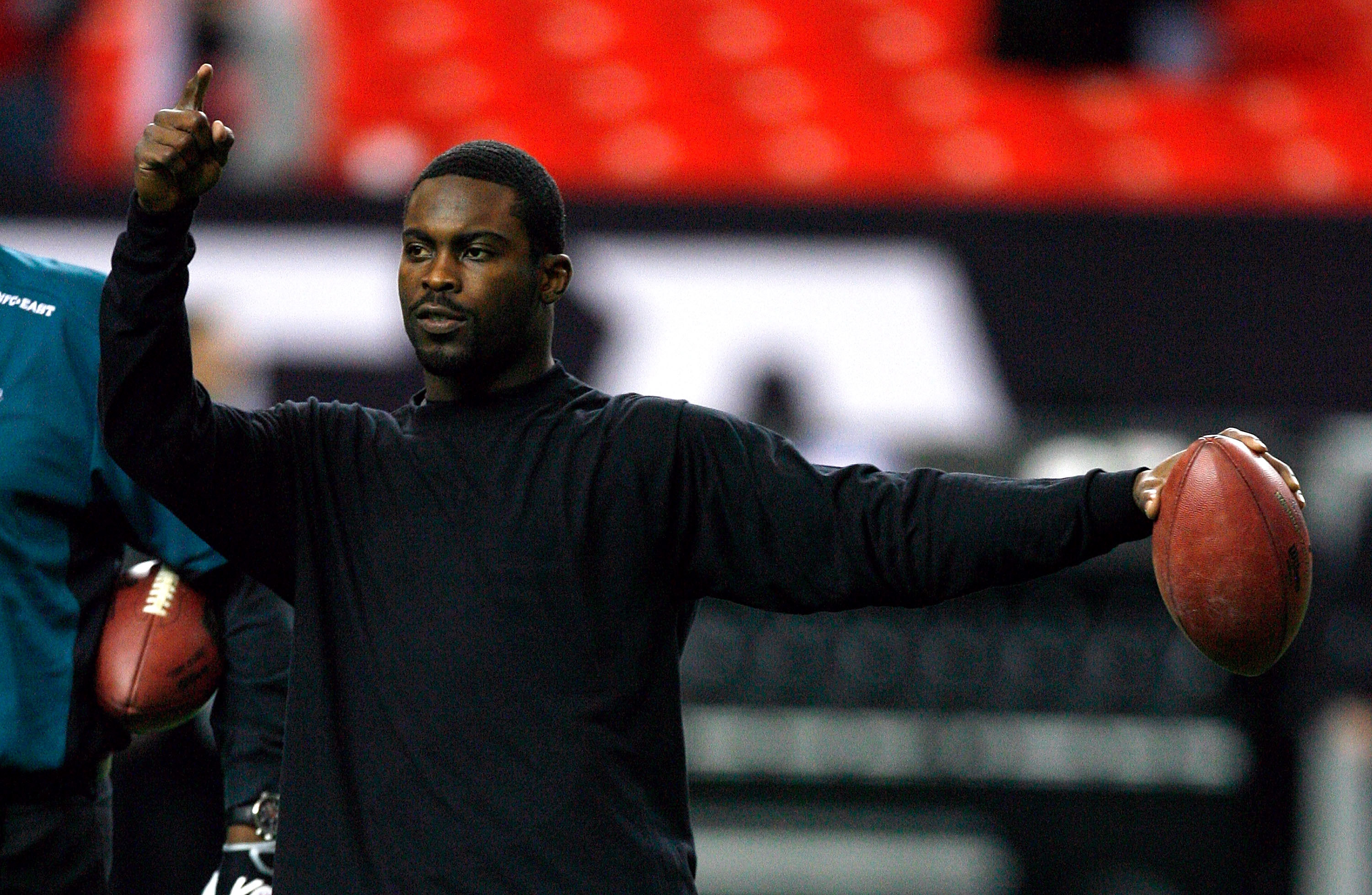 Former Atlanta Falcons Head Coach Jerry Glanville, left, stands with former Atlanta  Falcons quarterback Michael Vick on the turf before the first half of an  NFL football game between the Atlanta Falcons