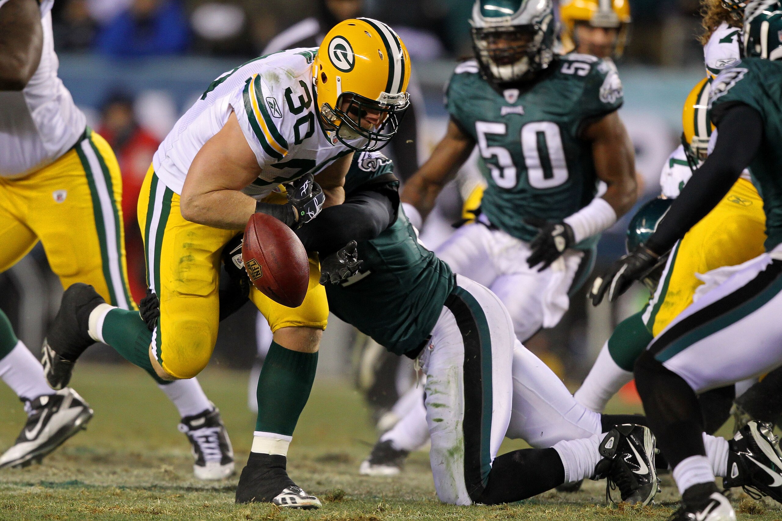 PHILADELPHIA, PA - JANUARY 09:  John Kuhn #30 of the Green Bay Packers loses the ball after getting tackled by Quintin Mikell #27 of the Philadelphia Eagles during the 2011 NFC wild card playoff game at Lincoln Financial Field on January 9, 2011 in Philad