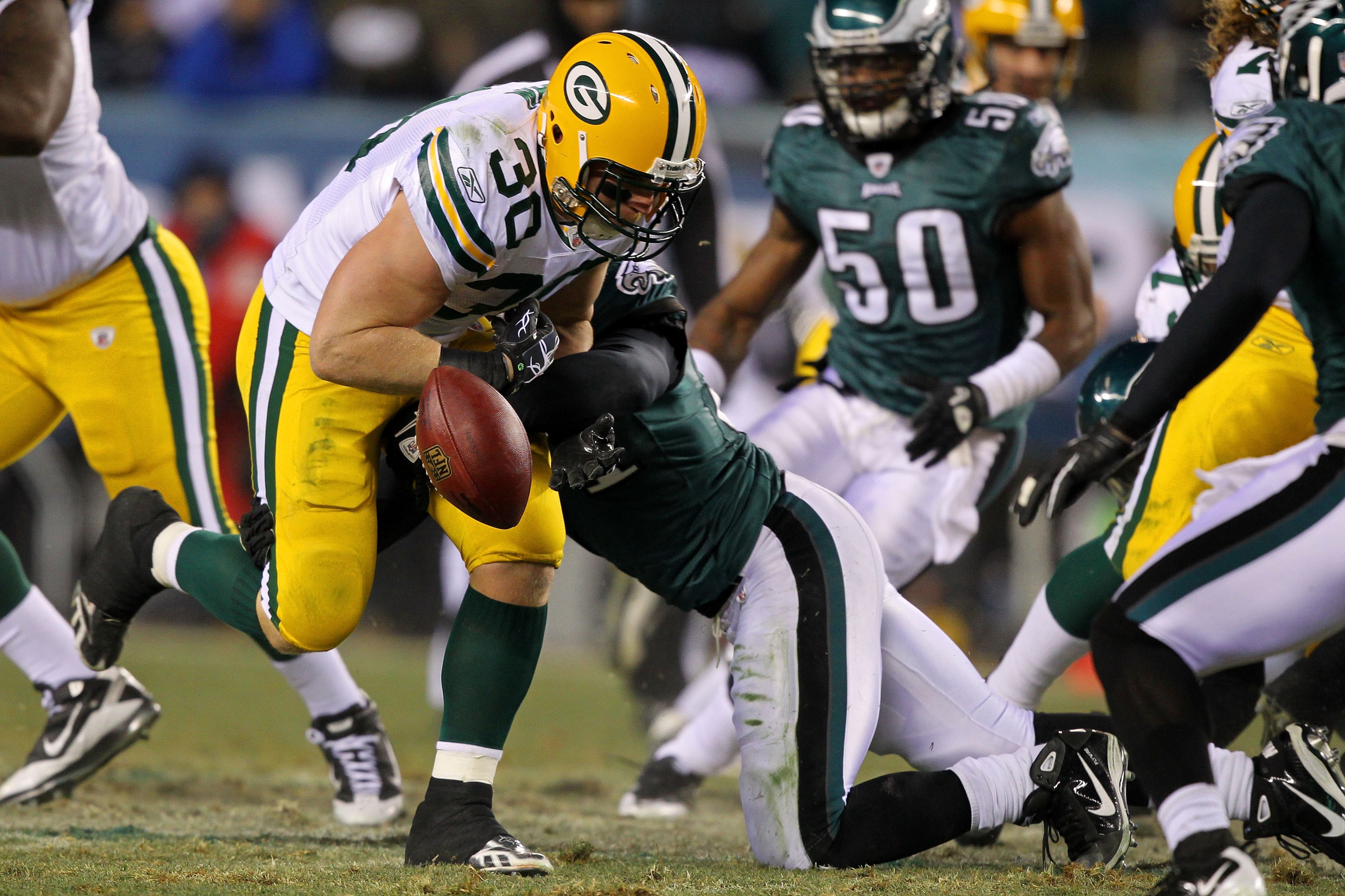 PHILADELPHIA, PA - JANUARY 09:  John Kuhn #30 of the Green Bay Packers loses the ball after getting tackled by Quintin Mikell #27 of the Philadelphia Eagles during the 2011 NFC wild card playoff game at Lincoln Financial Field on January 9, 2011 in Philad
