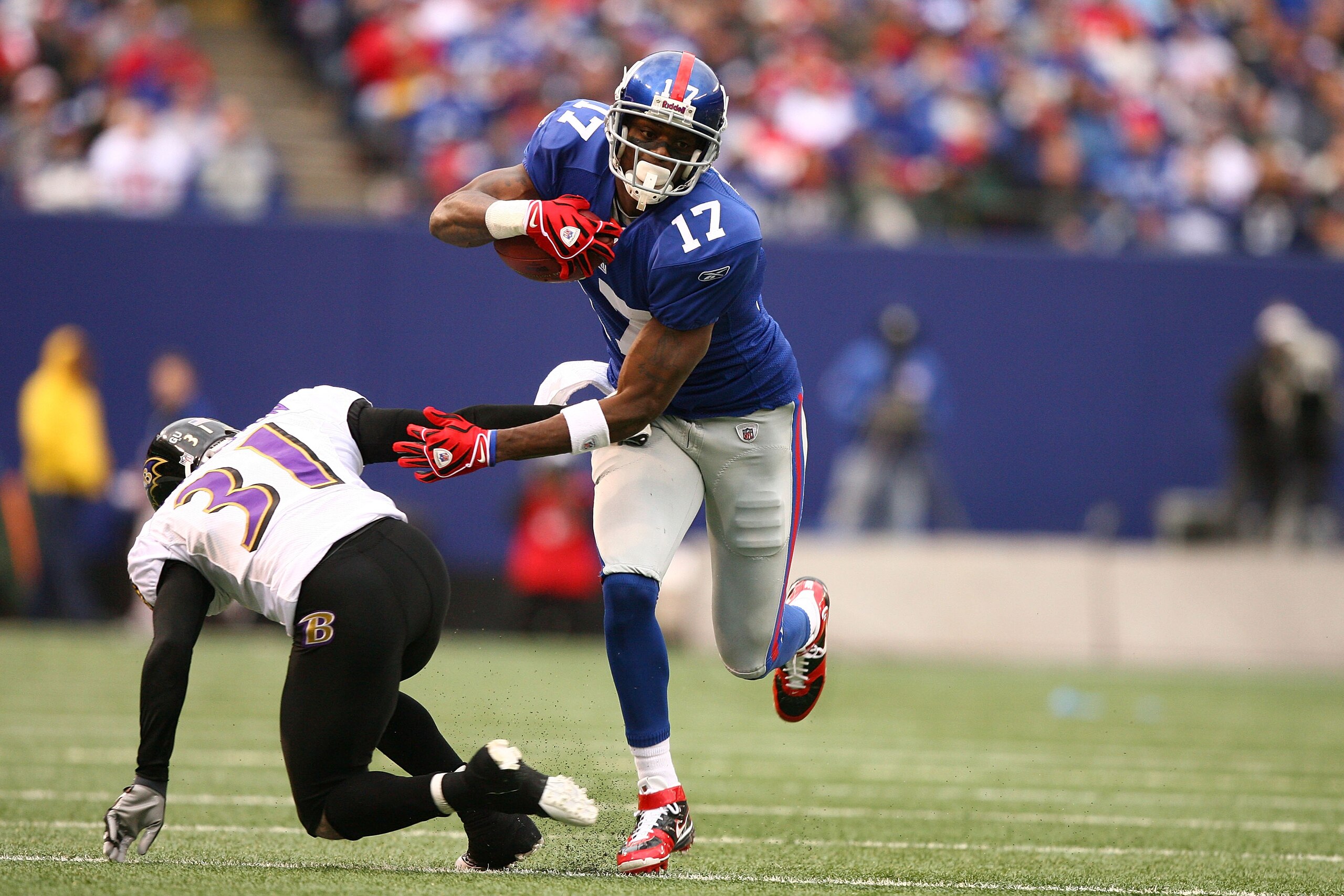 EAST RUTHERFORD, NJ - NOVEMBER 16:  Plaxico Burress #17 of the New York Giants eludes the tackle of Fabian Washington #31 of the Baltimore Ravens during their game on November 16, 2008 at Giants Stadium in East Rutherford, New Jersey.  (Photo by Al Bello/