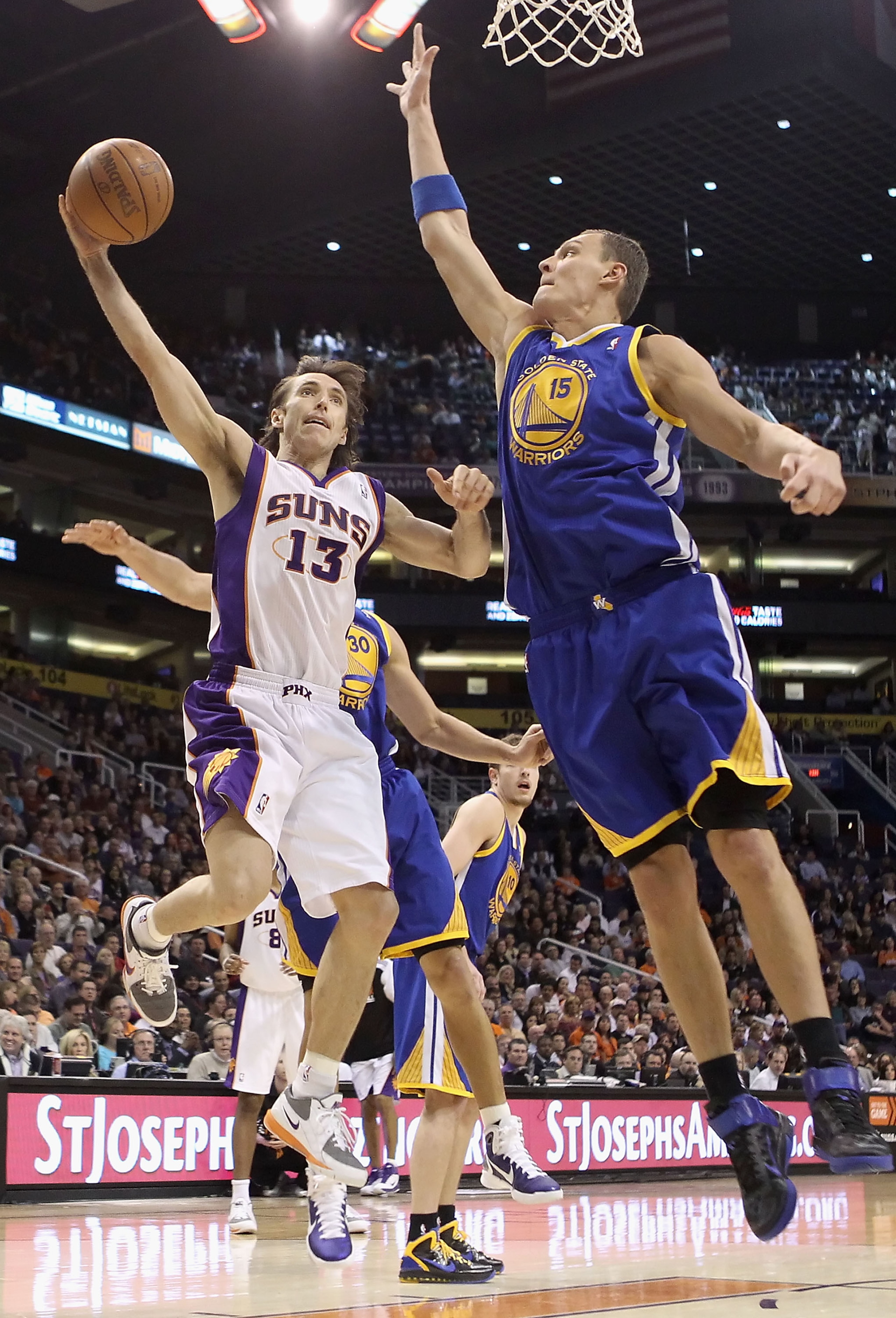 PHOENIX, AZ - FEBRUARY 10:  Steve Nash #13 of the Phoenix Suns lays up a shot past Andris Biedrins #15 of the Golden State Warriors during the NBA game at US Airways Center on February 10, 2011 in Phoenix, Arizona.  NOTE TO USER: User expressly acknowledg