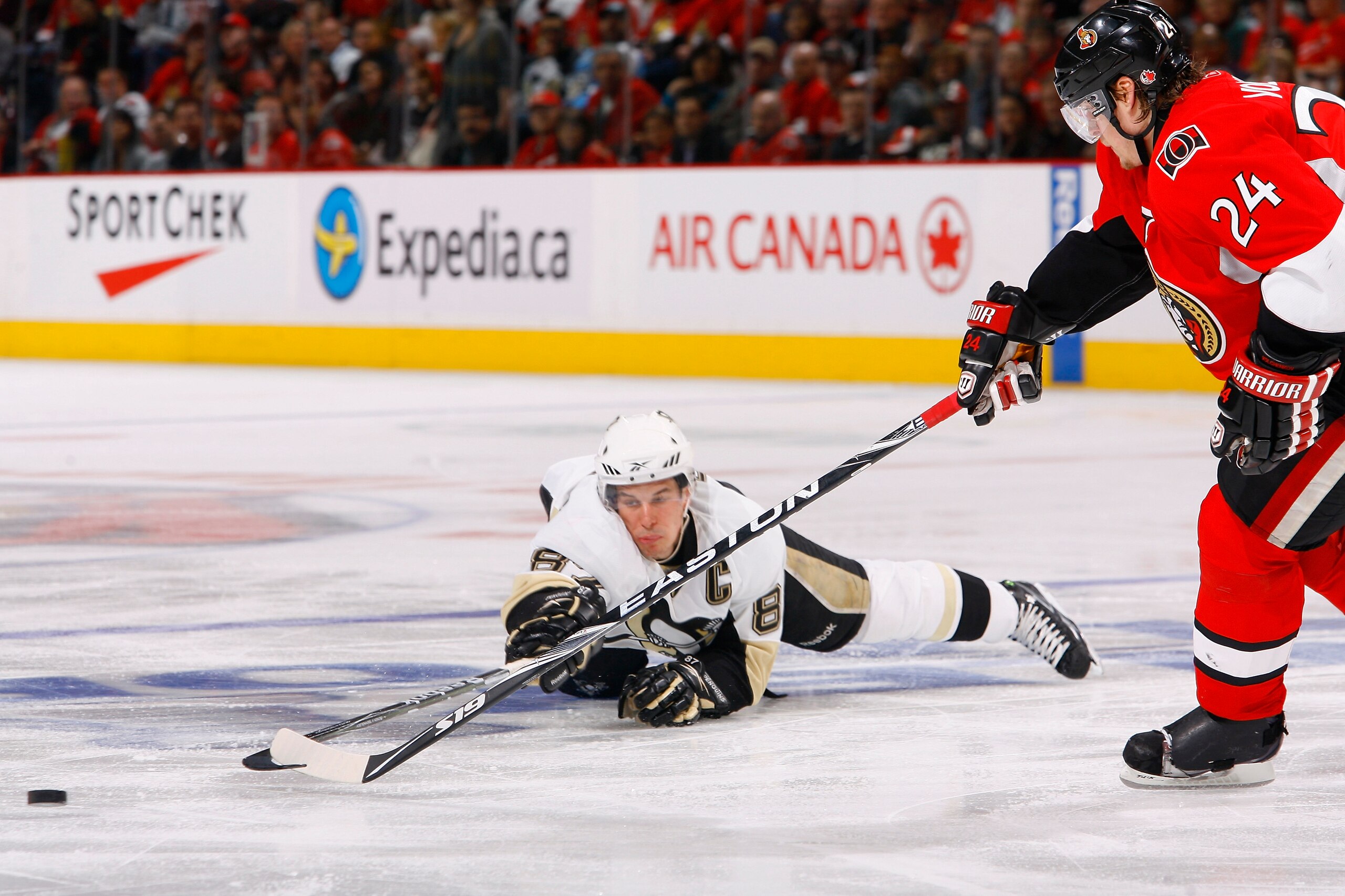OTTAWA, ON - APRIL 18:  Sidney Crosby #87 of the Pittsburgh Penguins dives to keep a puck in the offensive zone pushing it just out of reach of Anton Volchenkov #24 of the Ottawa Senators during Game 3 of the Eastern Conference Quaterfinals during the 201