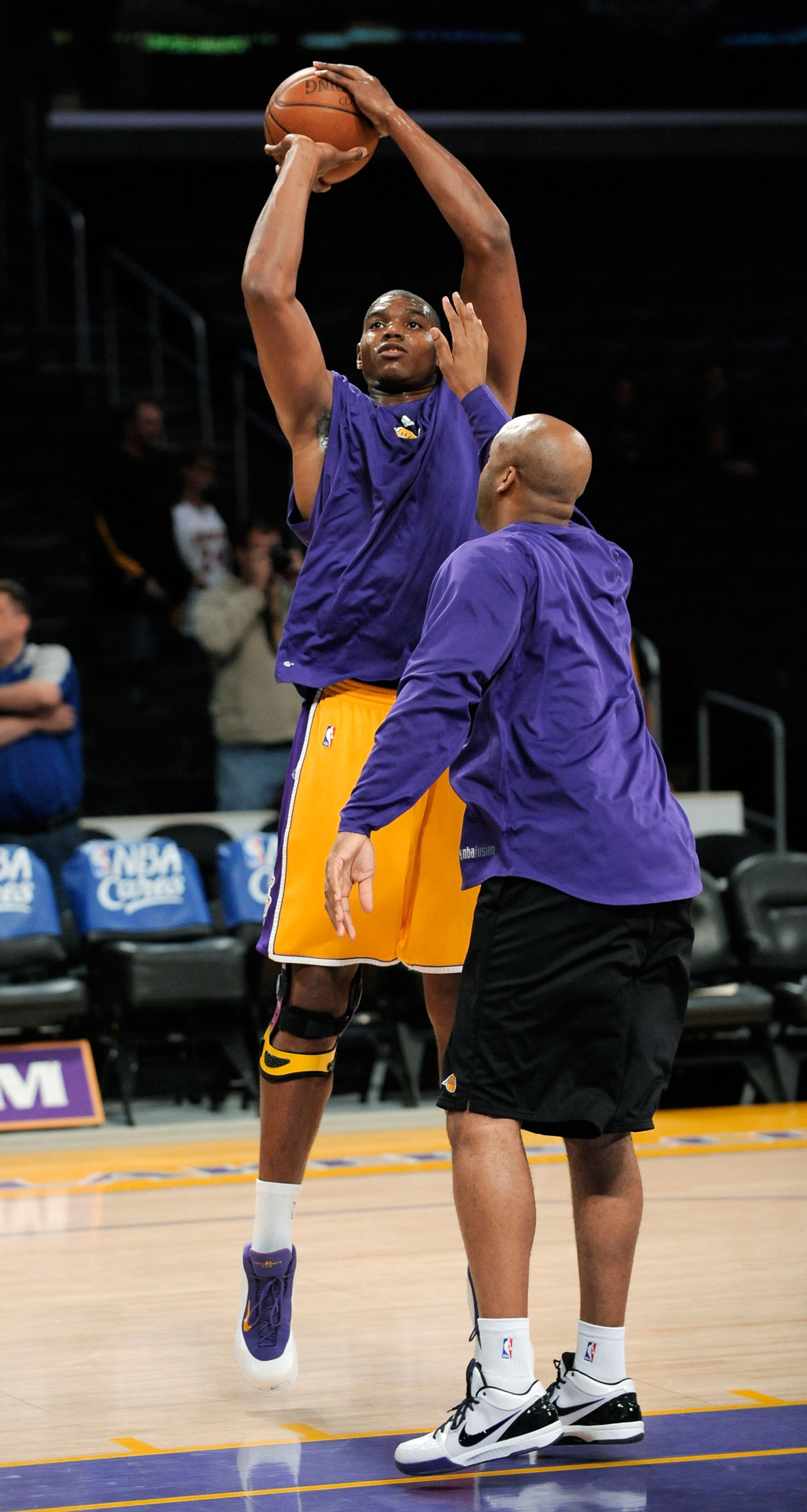 LOS ANGELES, CA - APRIL 9:  Andrew Bynum #17 (L) of the Los Angeles Lakers shoots a jumper as he warms up before the start of the game against the Denver Nuggets, his first game back after suffering a torn medial collateral ligament in his right knee on J