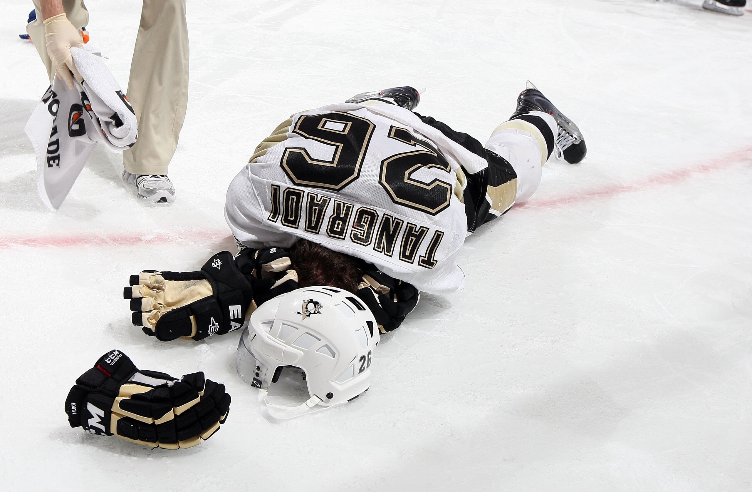 UNIONDALE, NY - FEBRUARY 11: Eric Tangradi #26 of the Pittsburgh Penguins lays on the ice after taking a hit to the head from Trevor Gillies (not pictured) of the New York Islanders on February 11, 2011 at Nassau Coliseum in Uniondale, New York. The Isle UNIONDALE, NY - FEBRUARY 11: Eric Tangradi #26 of the Pittsburgh Penguins lays on the ice after taking a hit to the head from Trevor Gillies (not pictured) of the New York Islanders on February 11, 2011 at Nassau Coliseum in Uniondale, New York. The Isle