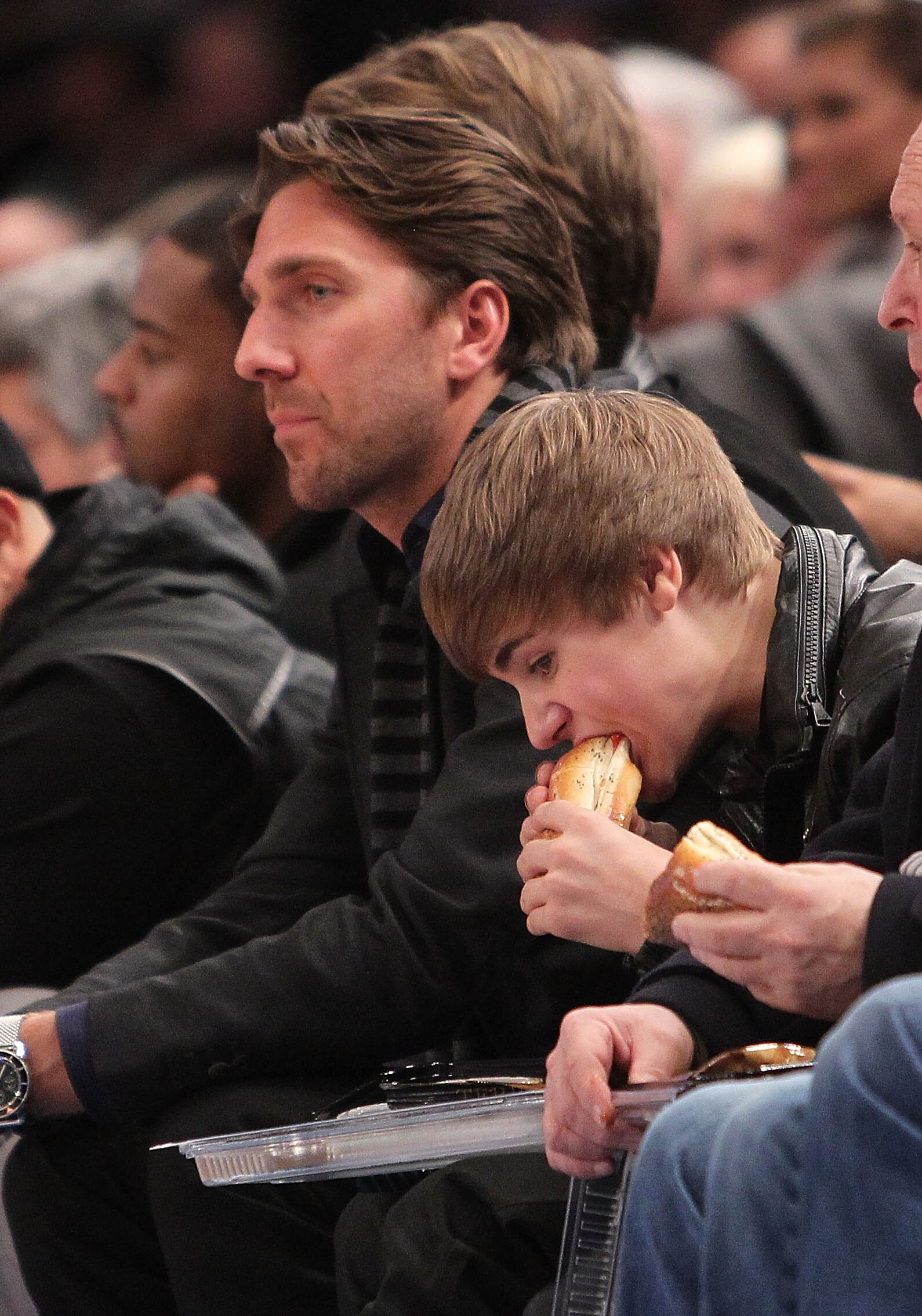 NEW YORK, NY - FEBRUARY 02:  Singer Justin Bieber eats a hotdog next to NHL player  Henrik Lundqvist   courtside during the game between the New York Knicks and the Dallas Mavericks at Madison Square Garden on February 2, 2011 in New York City. NOTE TO US