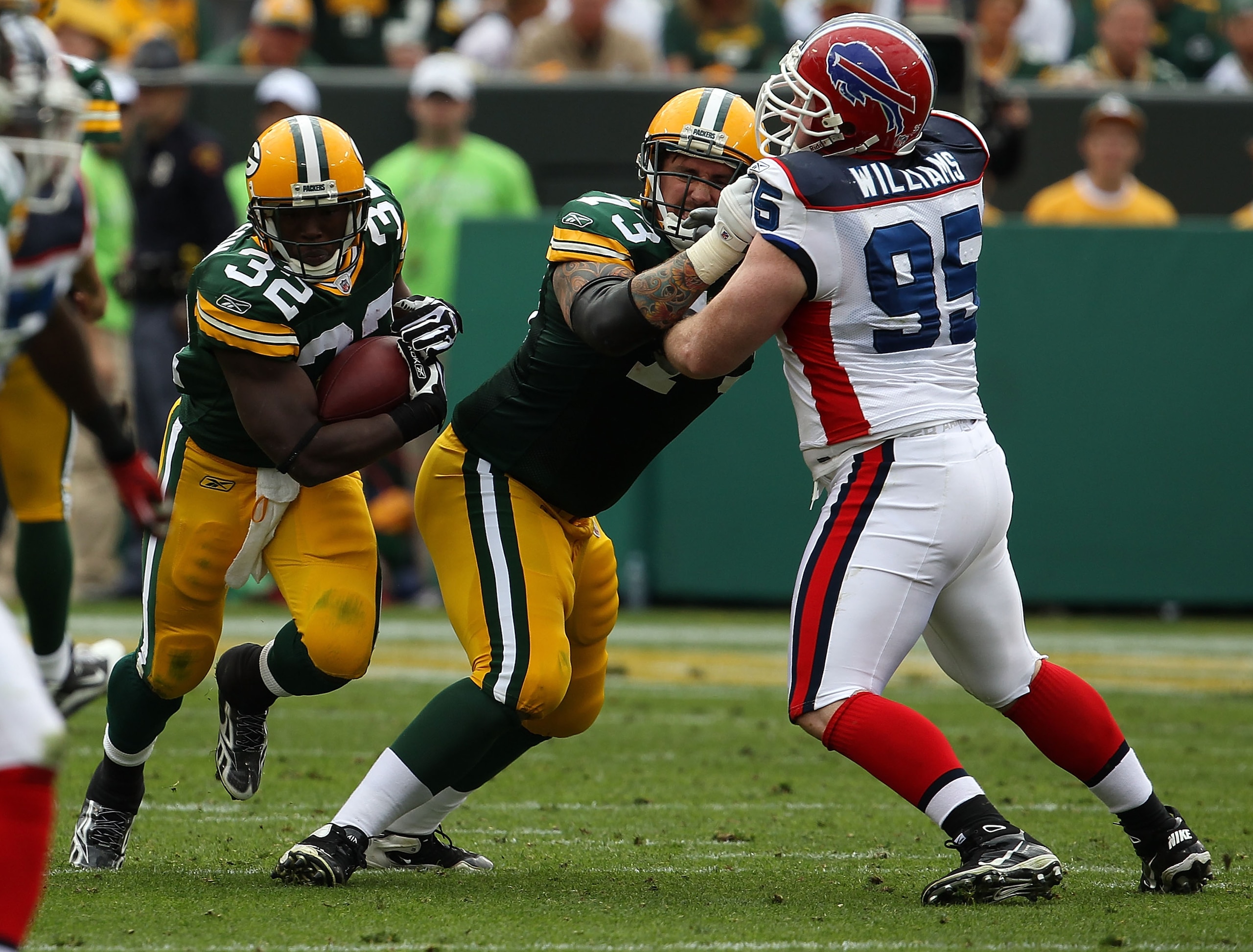 GREEN BAY, WI - SEPTEMBER 19: Brandon Jackson #32 of the Green Bay Packers runs as teammate Daryn Colledge #73 blocks Kyle Williams #95 of the Buffalo Bills at Lambeau Field on September 19, 2010 in Green Bay, Wisconsin. The Packers defeated the Bills 34-