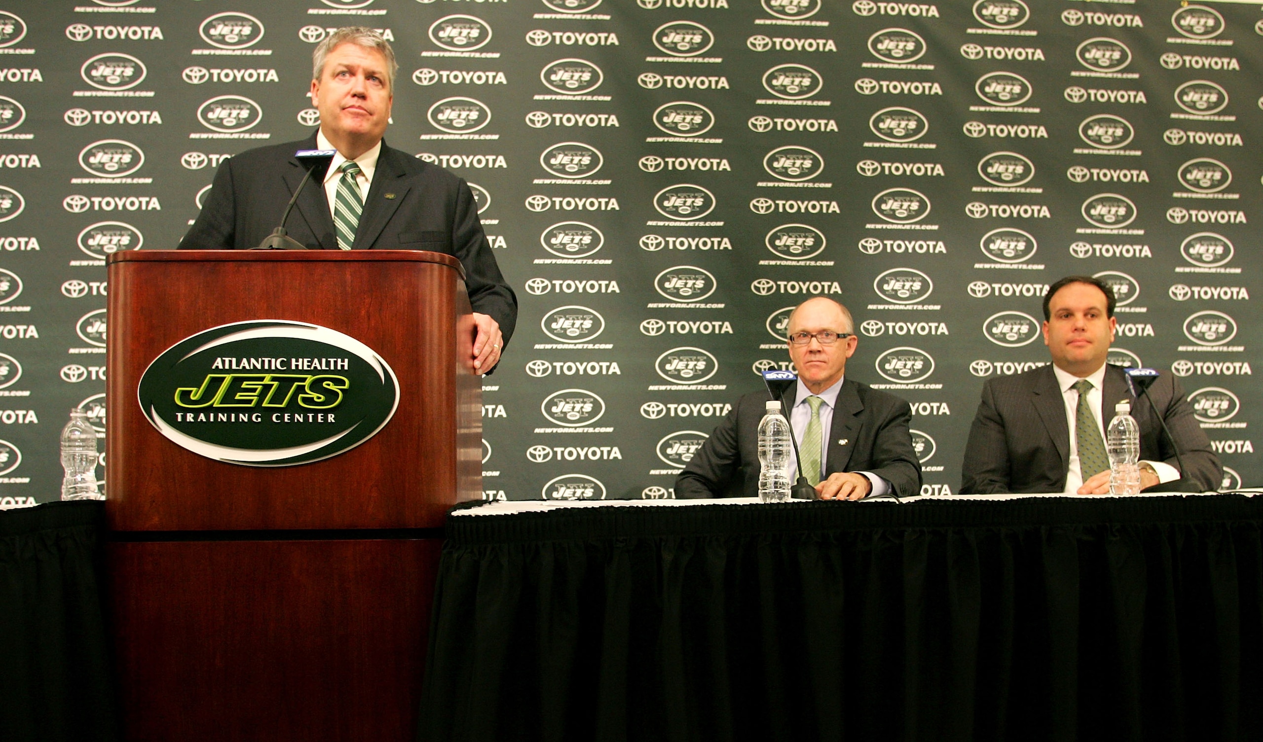 FLORHAM PARK, NJ - JANUARY 21: Rex Ryan addresses the media during a press conference introducing him as the new Head Coach of the New York Jets as Owner Woody Johnson (C) and General Manager Mike Tannenbaum look on at the Atlantic Health Jets Training C FLORHAM PARK, NJ - JANUARY 21: Rex Ryan addresses the media during a press conference introducing him as the new Head Coach of the New York Jets as Owner Woody Johnson (C) and General Manager Mike Tannenbaum look on at the Atlantic Health Jets Training C