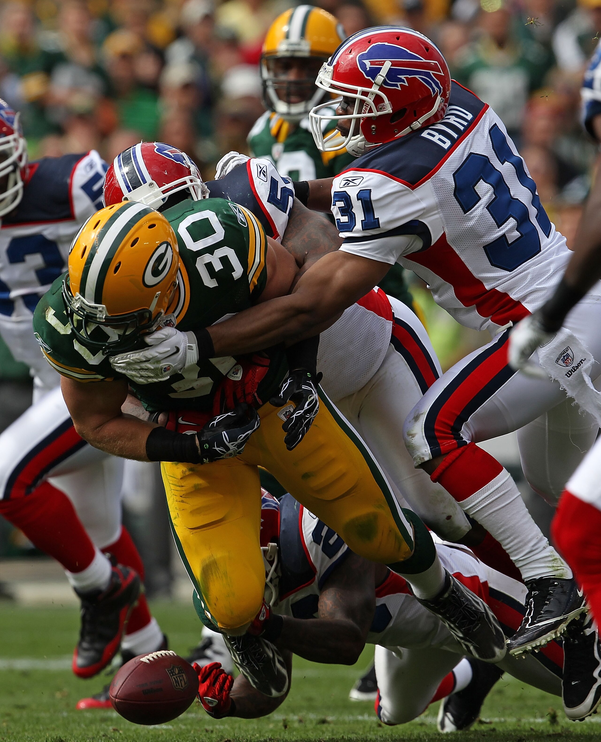 GREEN BAY, WI - SEPTEMBER 19: John Kuhn #30 of the Green Bay Packers fumbles the ball as he is hit by members of the Buffalo Bills defense including Jarius Byrd #31 at Lambeau Field on September 19, 2010 in Green Bay, Wisconsin. The Packers defeated the B