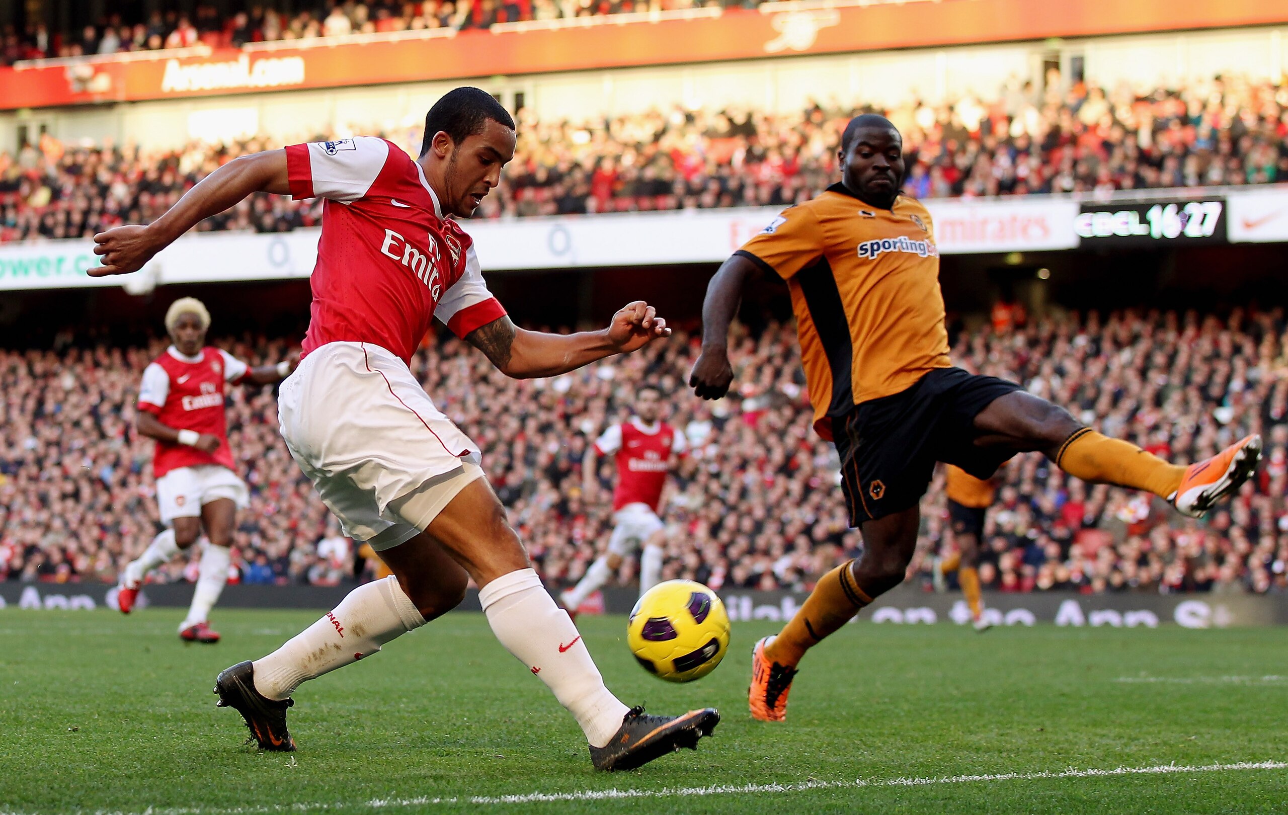 LONDON, ENGLAND - FEBRUARY 12:  Theo Walcott of Arsenal (L) attempts to cross the ball past George Elokobi of Wolves during the Barclays Premier League match between Arsenal and Wolverhampton Wanderers on February 12, 2011 in London, England.  (Photo by S