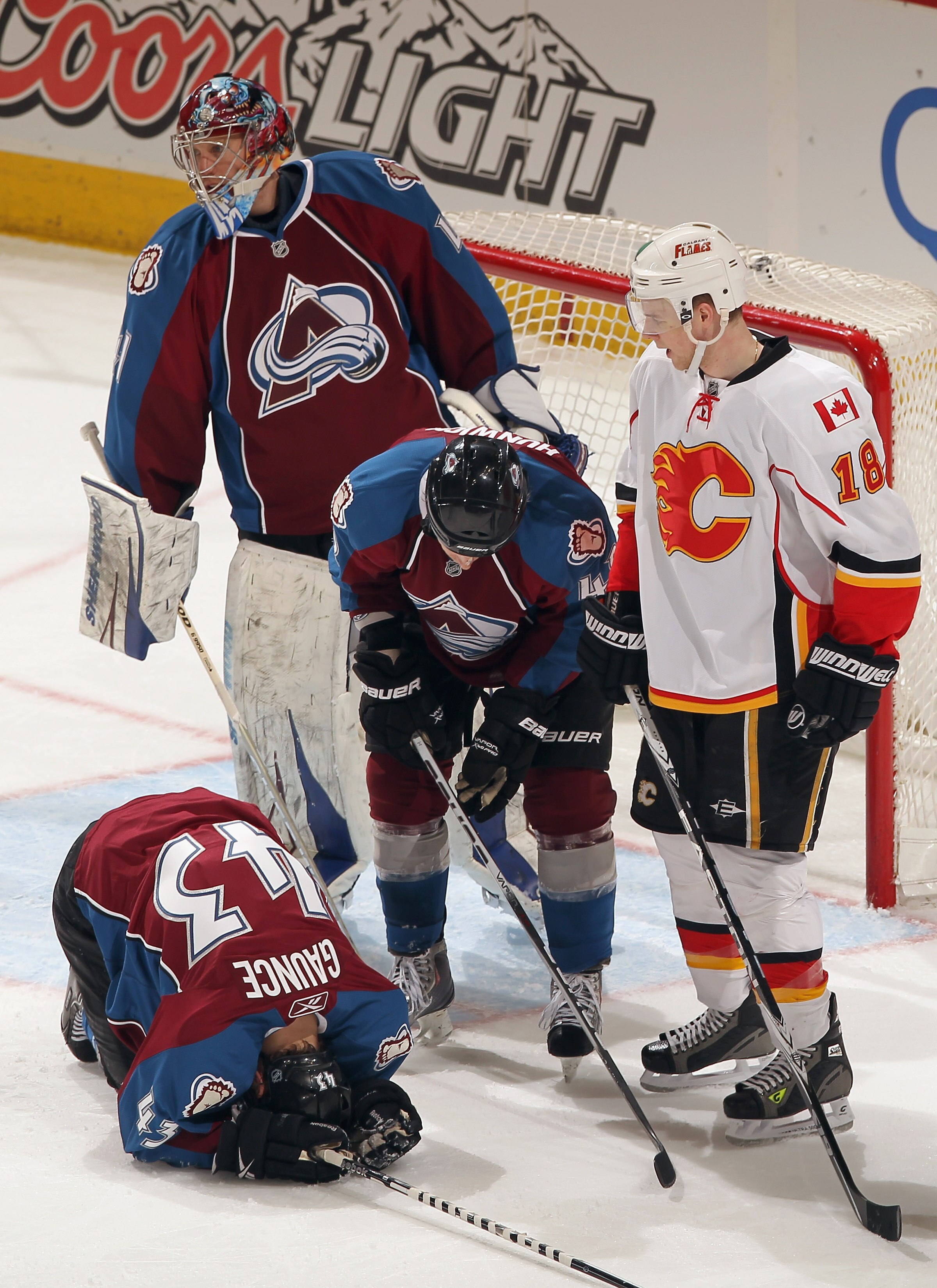 DENVER, CO - FEBRUARY 14:  Cameron Gaunce #43 of the Colorado Avalanche falls to the ice with an injury as goalie Craig Anderson #41 and John Michael Liles #4 of the Avalanche and Matt Stajan #18 of the Calgary Flames look on at the Pepsi Center on Februa