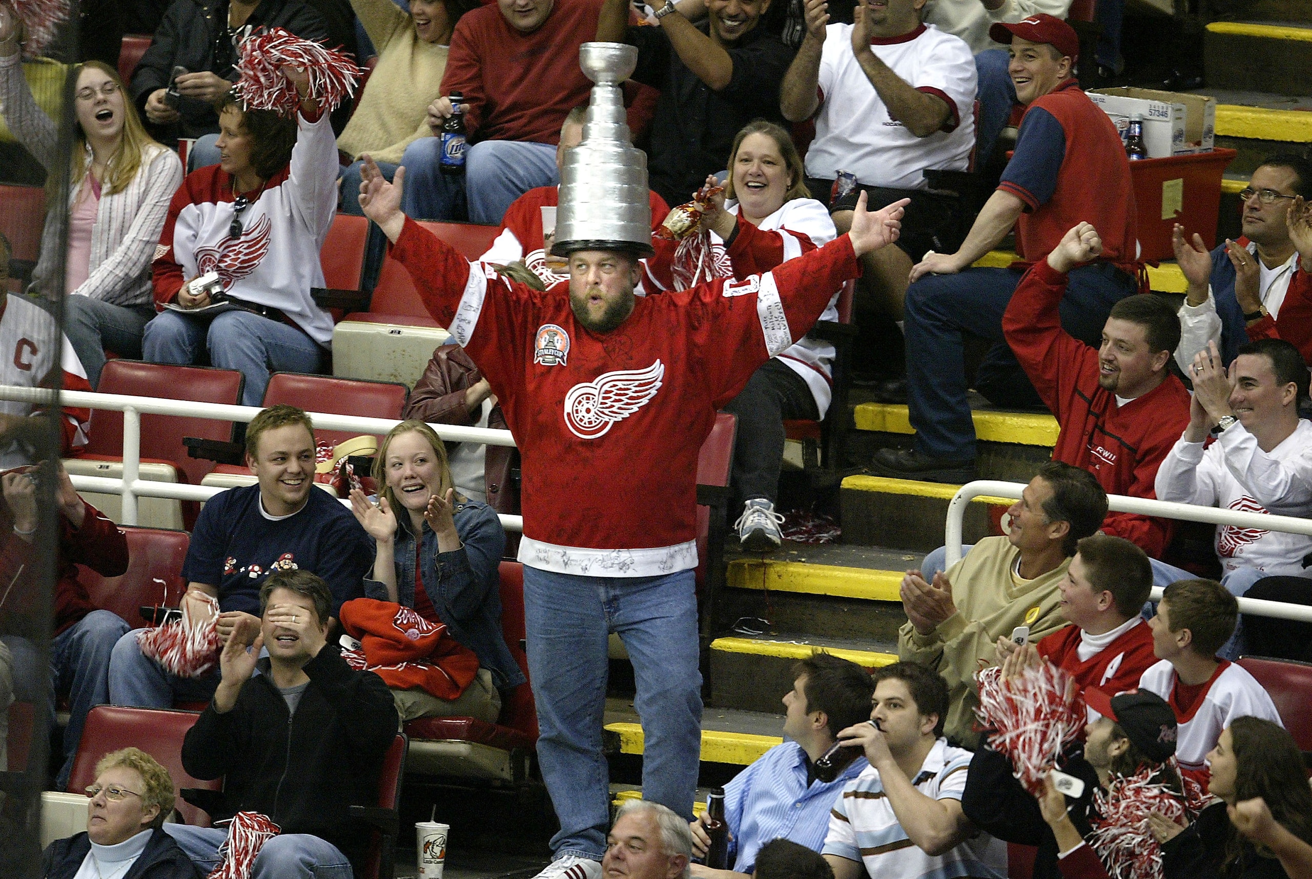 DETROIT - APRIL 24:  A Detroit Red Wings fan dances in the aisle wearing a mock Stanley Cup in the second period of a game against the Calgary Flames during the second round of the Stanley Cup Playoffs, game two at Joe Louis Arena on April 24, 2004 in Det