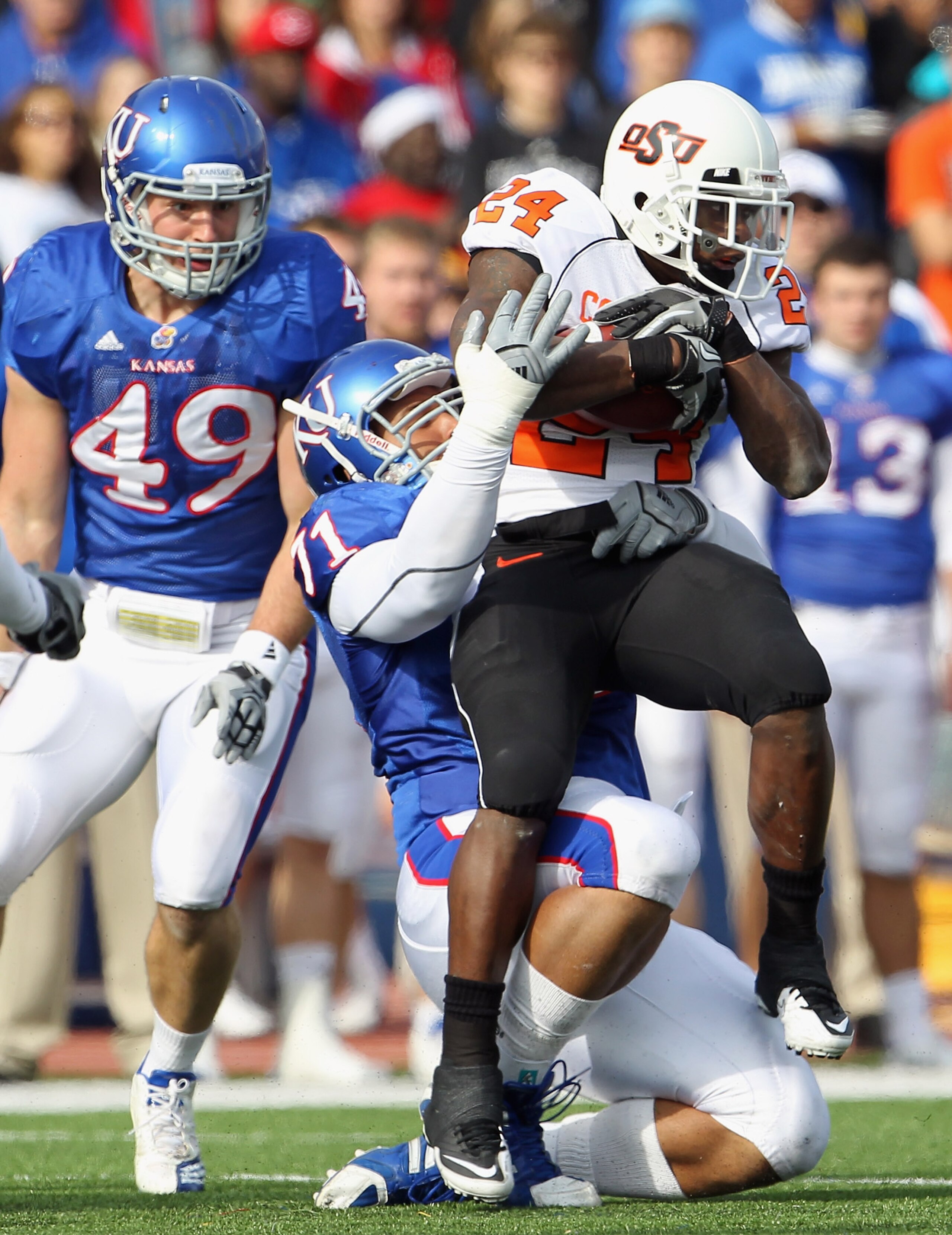 LAWRENCE, KS - NOVEMBER 20:  Running back Kendall Hunter #24 of the Oklahoma State Cowboys is pulled down by John Williams #71 of the Kansas Jayhawks during the game on November 20, 2010 at Memorial Stadium in Lawrence, Kansas.  (Photo by Jamie Squire/Get