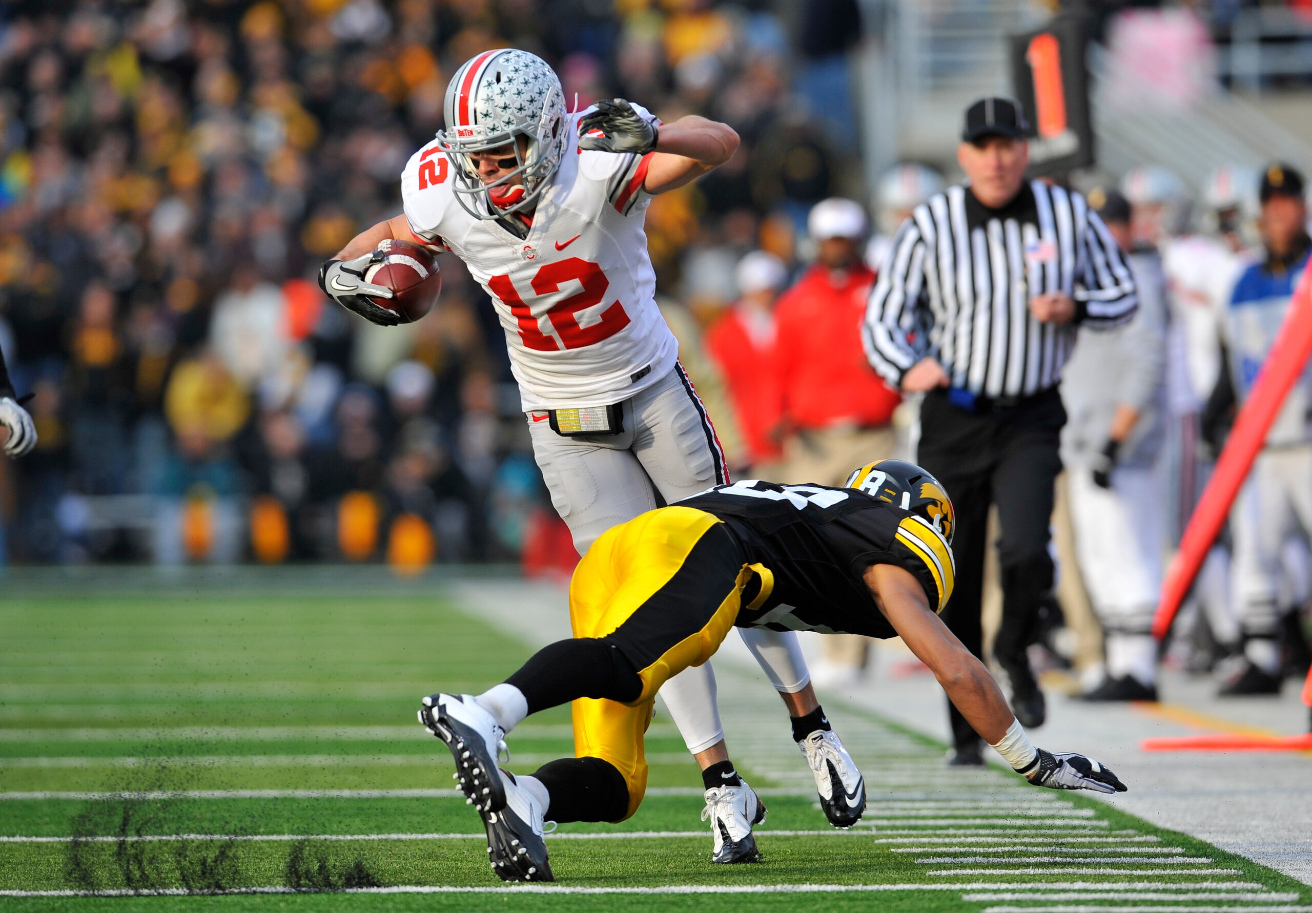 IOWA CITY, IA - NOVEMBER 20:  Defenisve back Micah Hyde #18 of the University of Iowa Hawkeyes trips up wide receiver Dane Sanzenbacher #12 of the Ohio State Buckeyes as he drove the ball down field during the first half of play at Kinnick Stadium on Nove